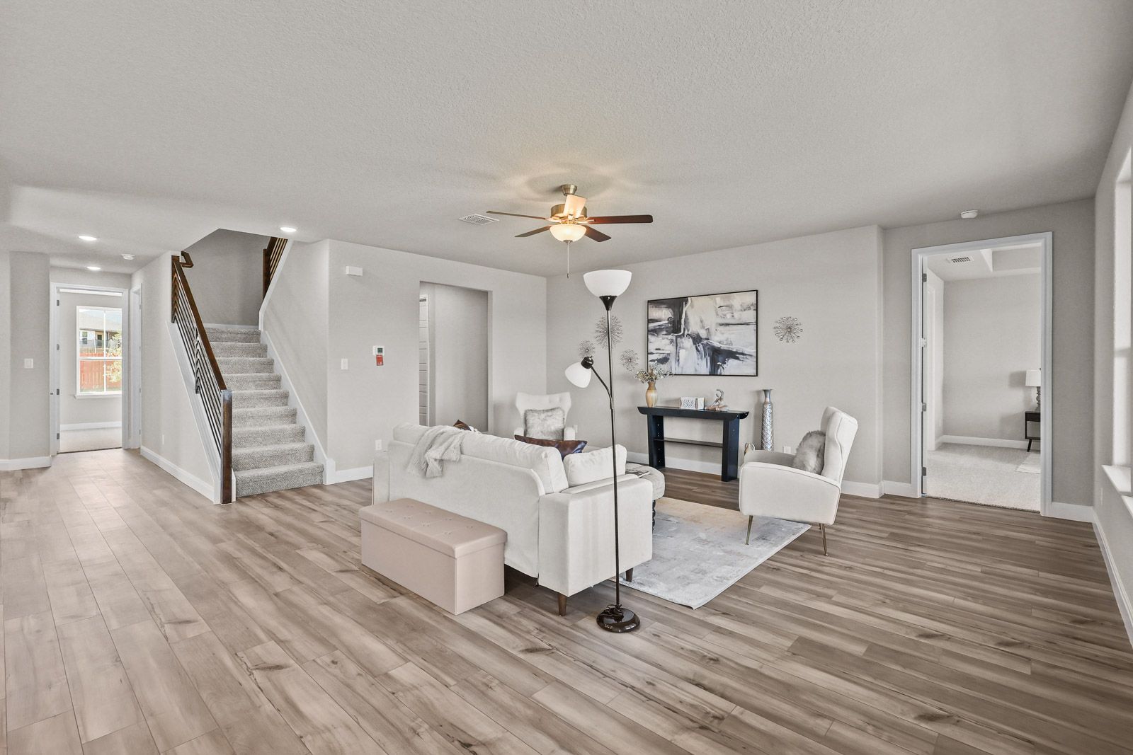 Open-concept living area in The Jennings G featuring modern furniture, wood-look flooring, and a staircase.