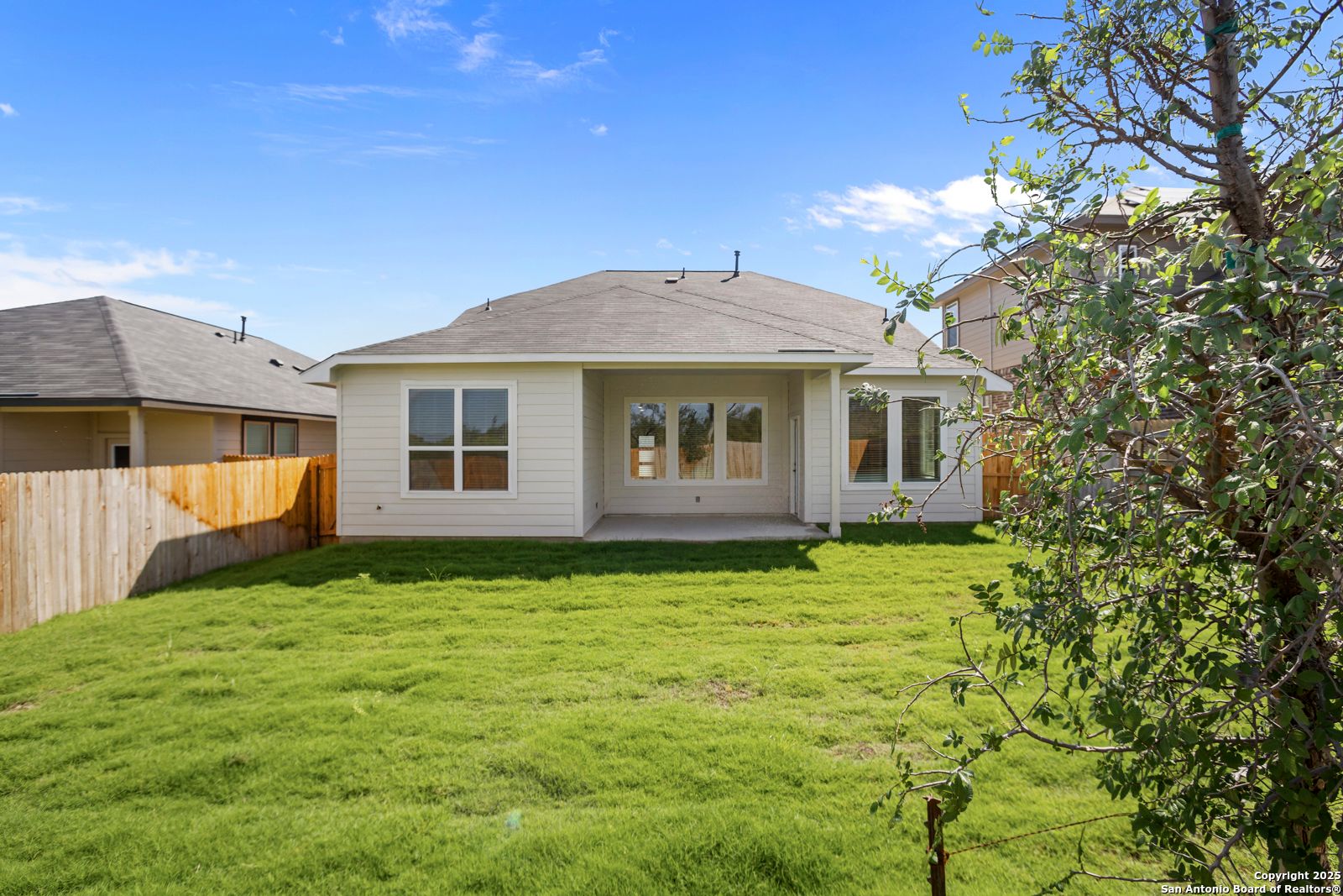 Rear view of Davidson Homes Sequoia A featuring covered patio, large windows, lush green backyard and wooden fence in Horizon Pointe, Converse, Texas