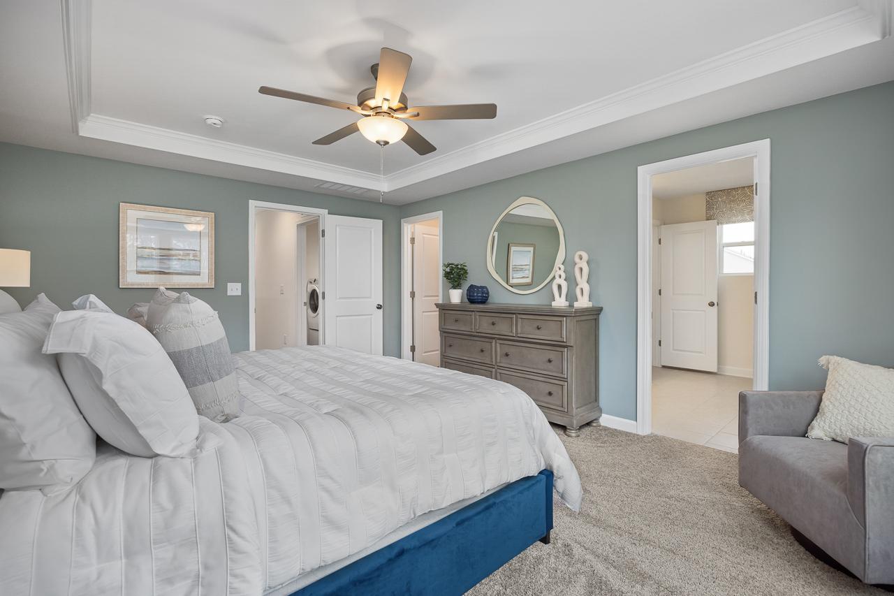Spacious primary bedroom at Gregory Village Townhomes in Lillington NC with king bed, gray walls, ceiling fan and en-suite doors