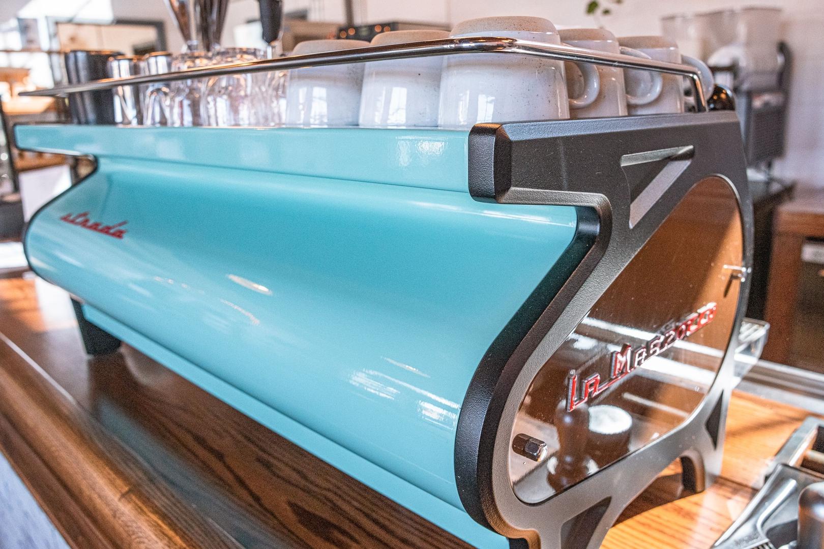Vibrant turquoise La Marzocco espresso machine on wooden counter in Ivy Glen community cafe, Perry Georgia by Evermore Homes