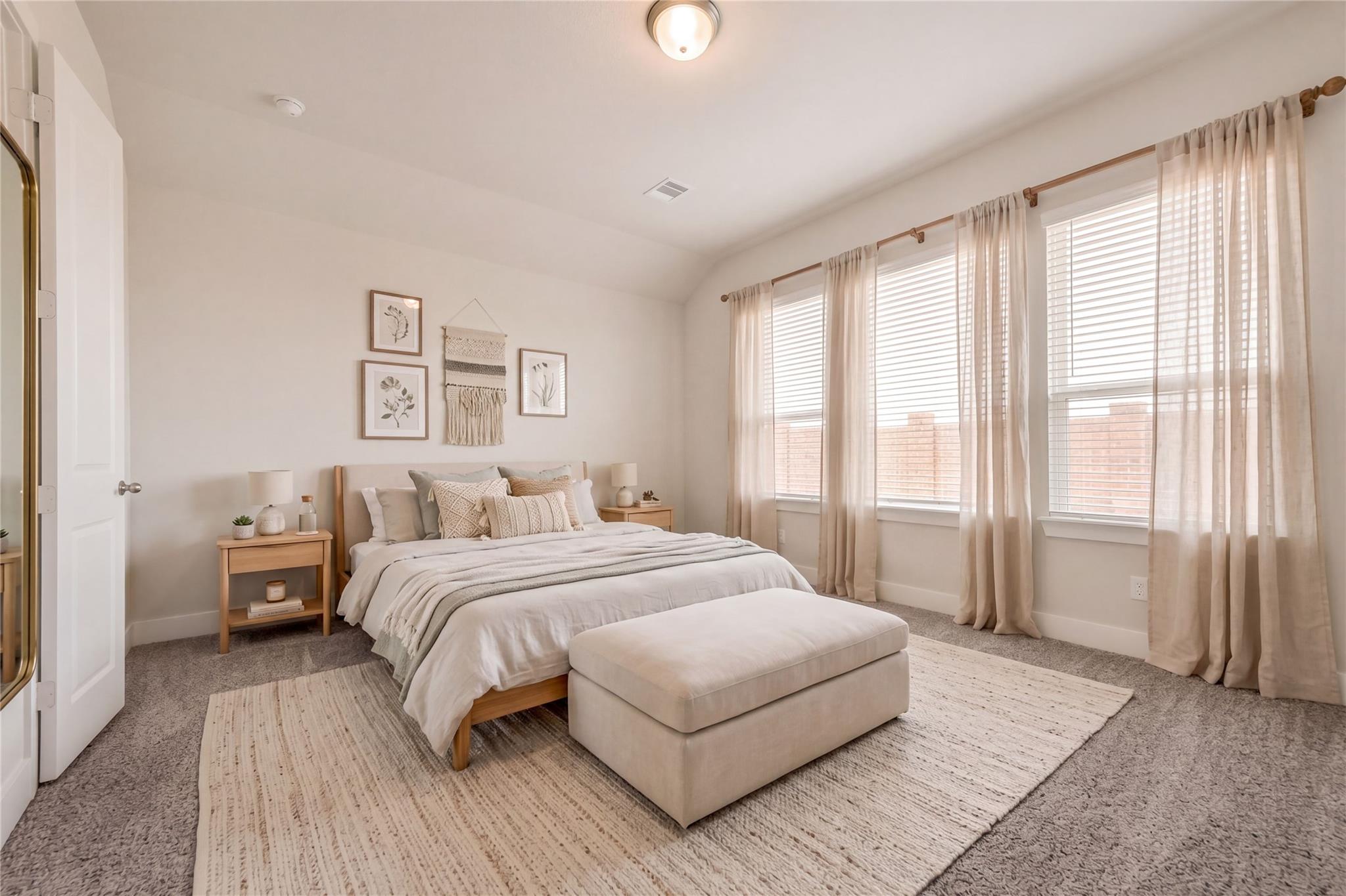 Serene master bedroom with king bed, neutral bedding, sheer curtains on large windows, wall art, and ottoman in Davidson Homes The Victoria A, Lago Mar