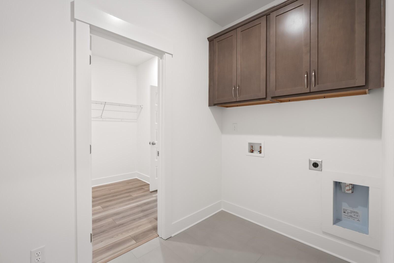 Modern laundry room featuring upper wood cabinets, white utility sink, washer/dryer hookups in Davidson Homes The Ash C, Mt. Juliet, TN