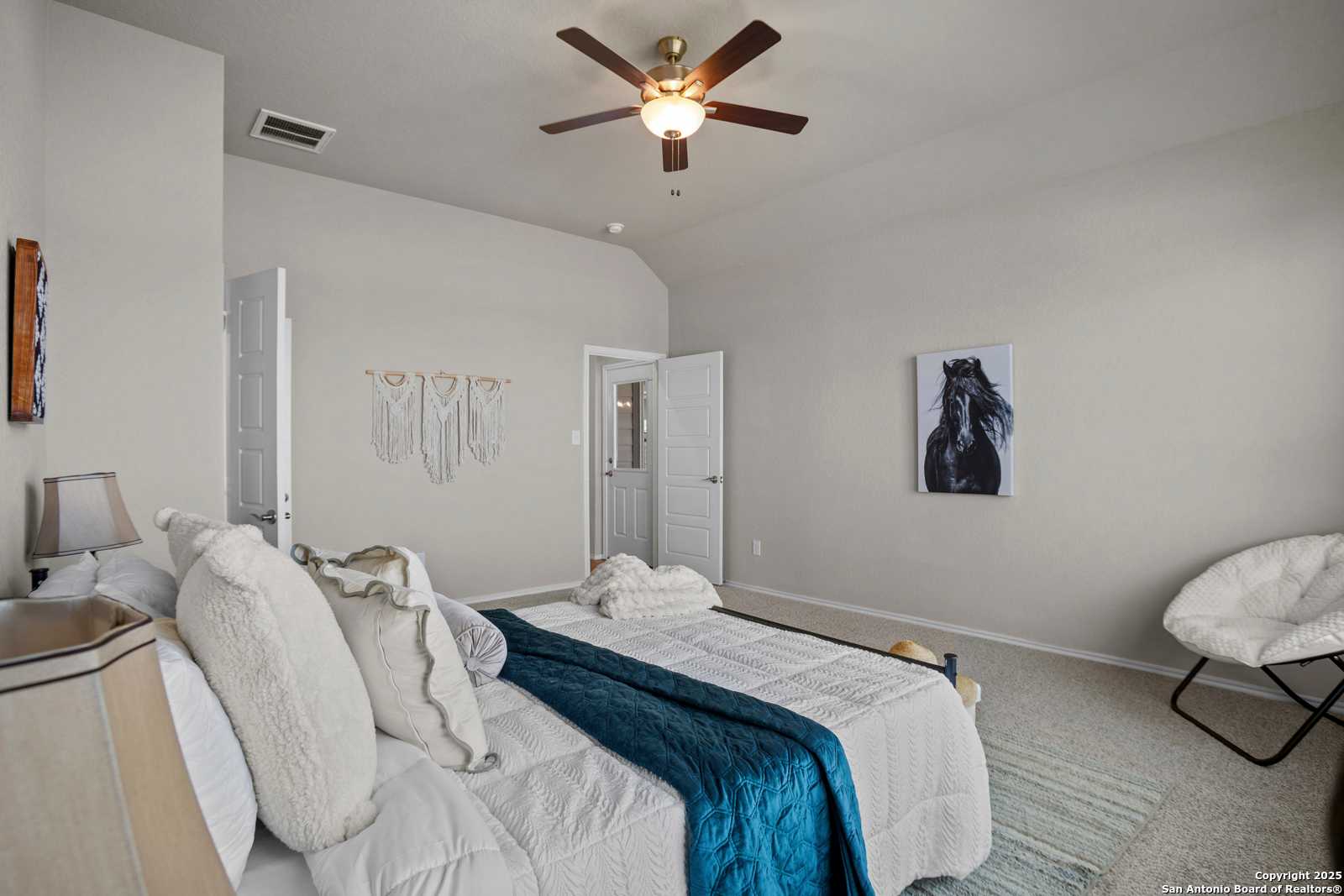 Cozy secondary bedroom with plush bed, bohemian decor, horse artwork and ceiling fan in Davidson Homes The Collin B, Seguin, TX