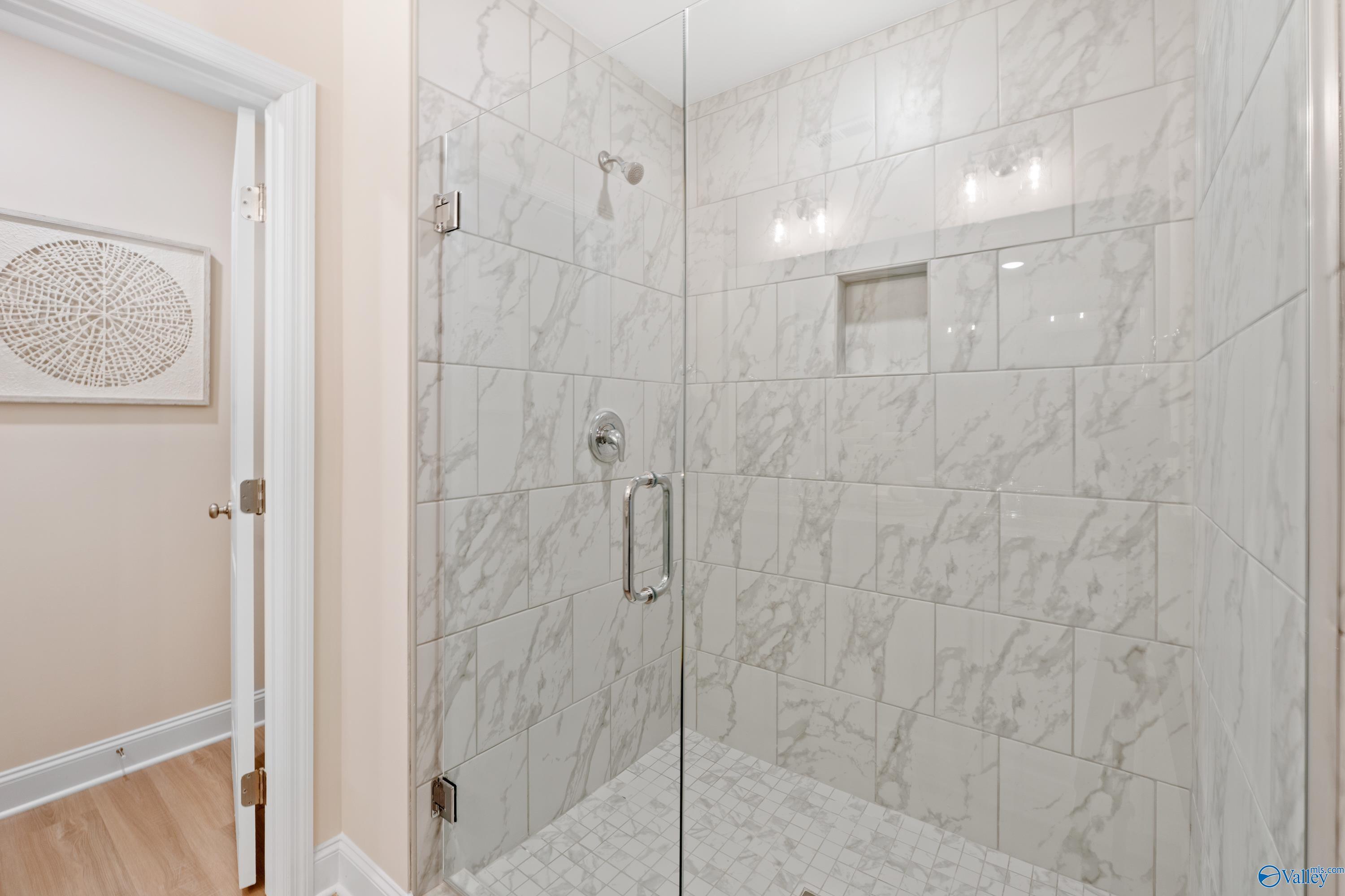 Elegant master bathroom with frameless glass shower, white subway tile, and niche shelves in Davidson Homes The Camden, Huntsville, Alabama