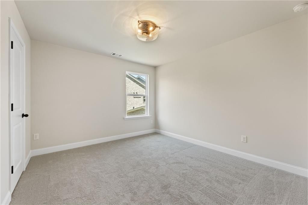 Cozy secondary bedroom with beige walls, gray carpet, ceiling light, and large window in Davidson Homes The Hickory E, Buford, GA