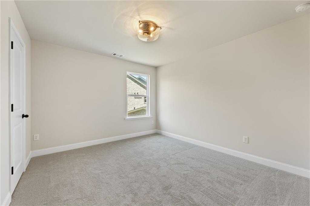 Bright secondary bedroom featuring beige walls, gray carpet, window view, and chandelier in Davidson Homes The Hickory E, Buford, GA