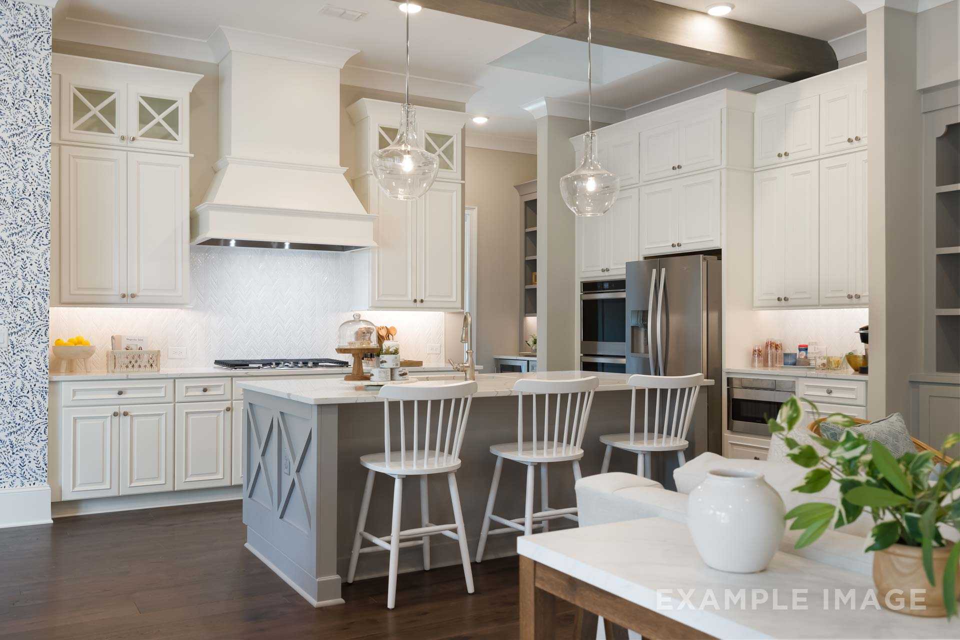 Spacious gourmet kitchen in The Seaside with white shaker cabinets, gray island, bar stools, stainless appliances, subway tile