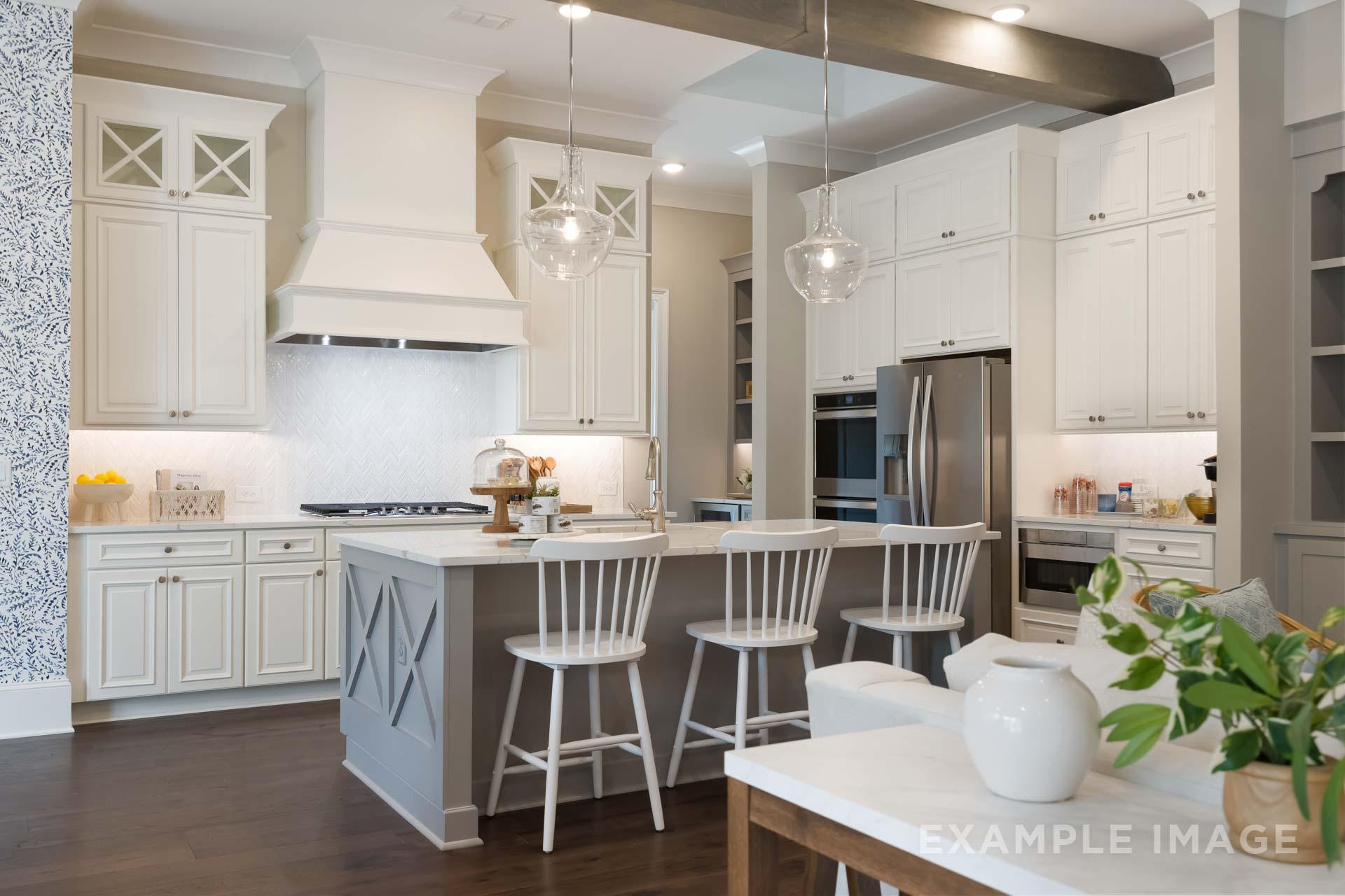 Spacious gourmet kitchen in The Seaside C featuring white cabinets, gray island with barstools, stainless appliances, subway backsplash