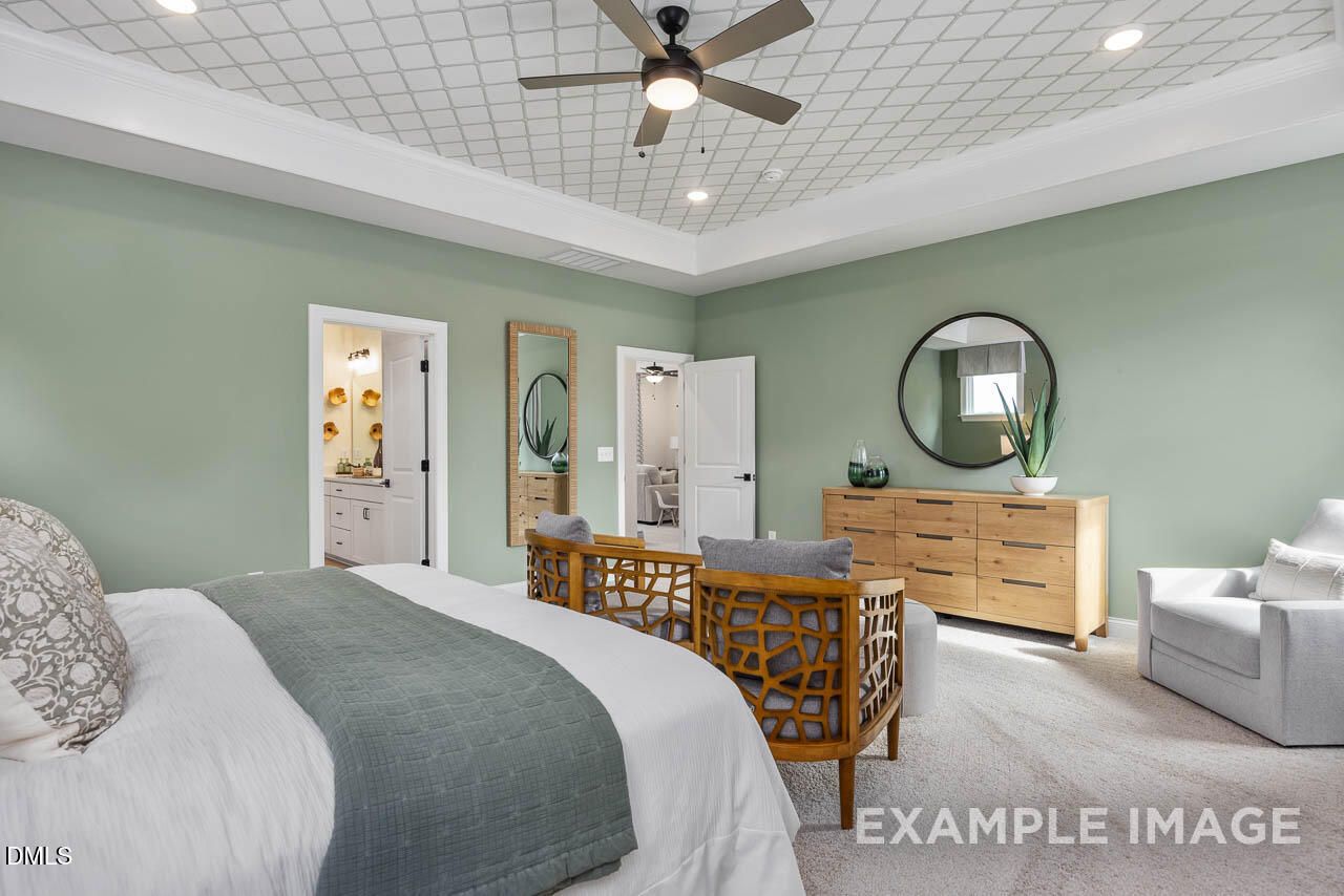 Serene master bedroom with sage green walls, tray ceiling fan, round mirror, and en-suite bath in Davidson Homes The Crawford D, Angier, NC