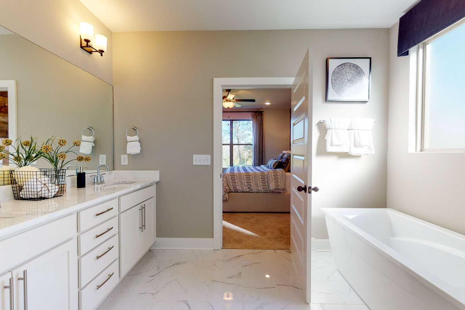Spacious master bathroom at Liberty Creek in Gallatin TN with freestanding tub, white double vanity, and bedroom view through open door