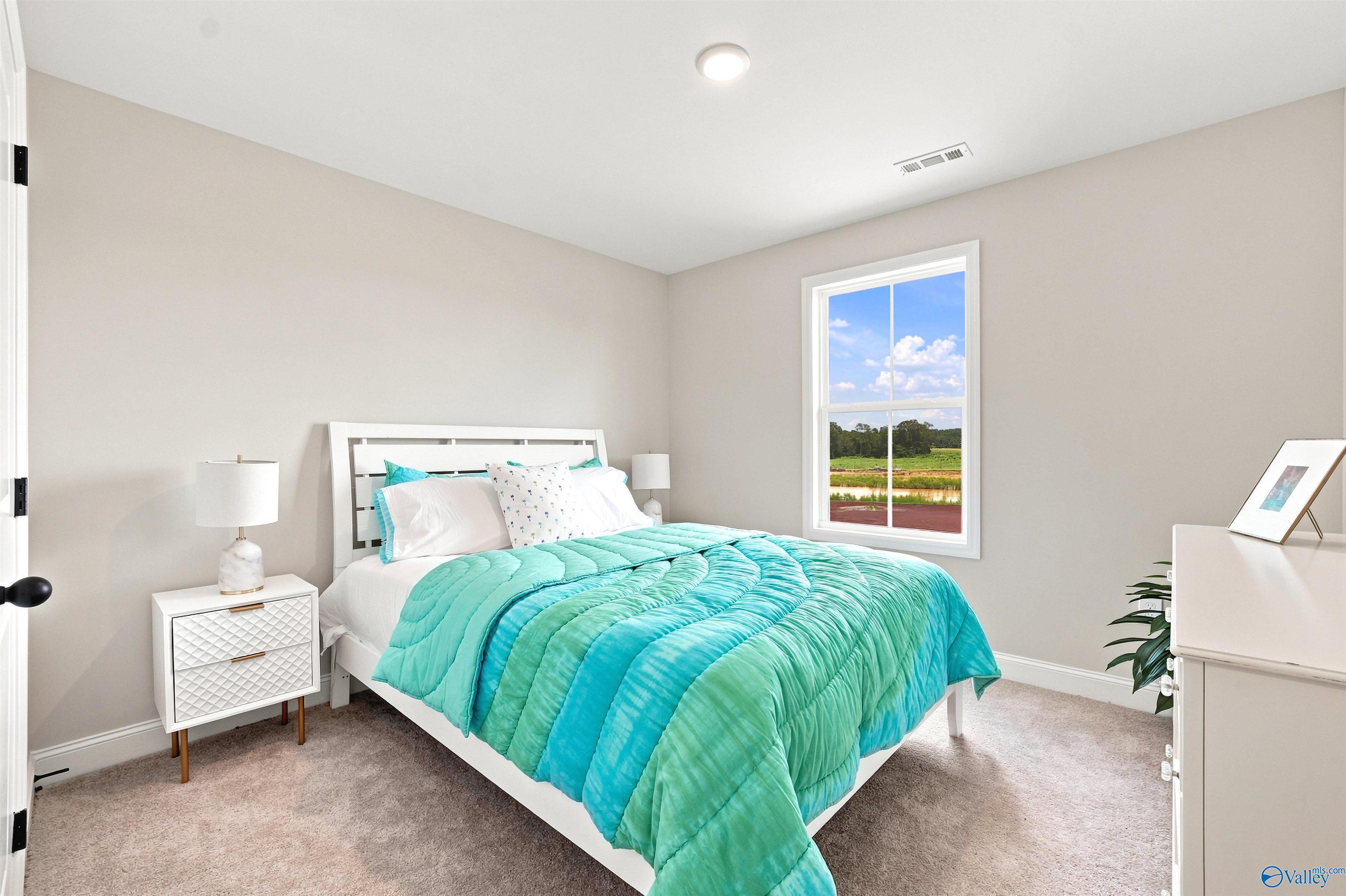 Bright, cozy bedroom with teal bedding in The Burton B floor plan at Heritage Lakes, New Market, Alabama.