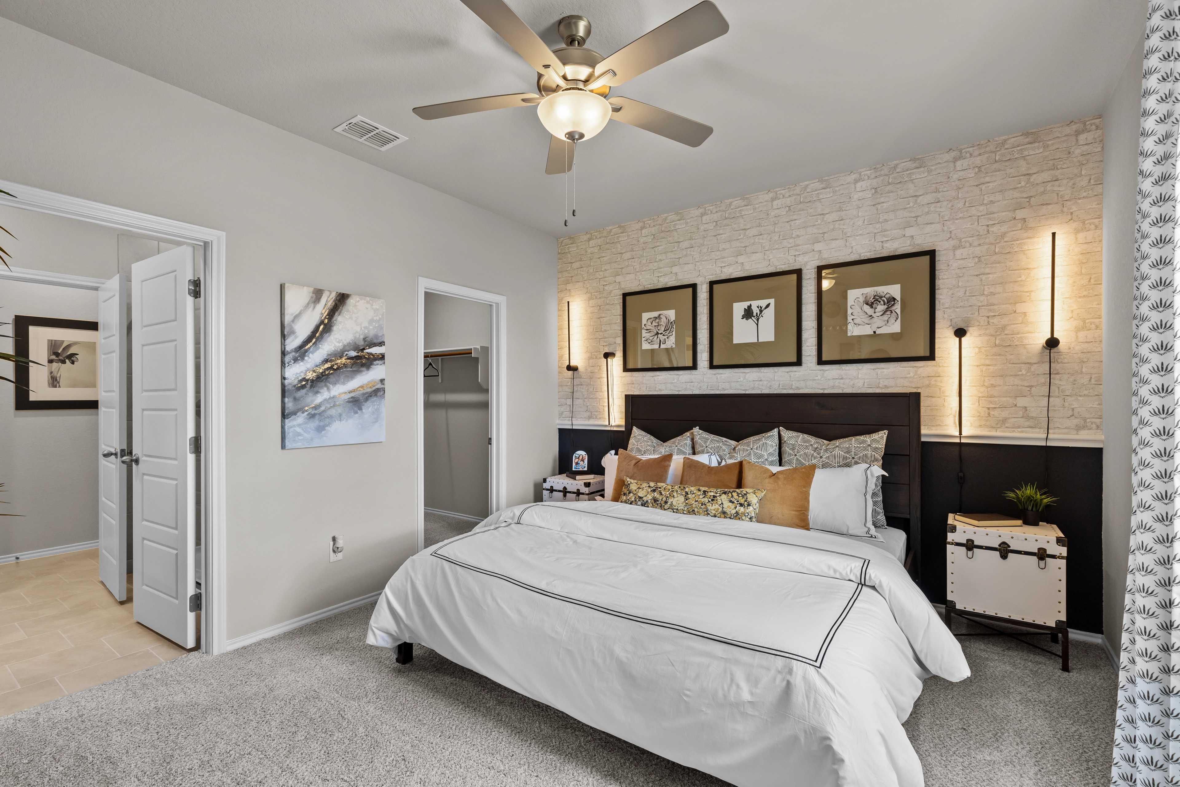 Spacious primary bedroom in Applewhite Meadows San Antonio TX with king bed, neutral walls, artwork, and ceiling fan