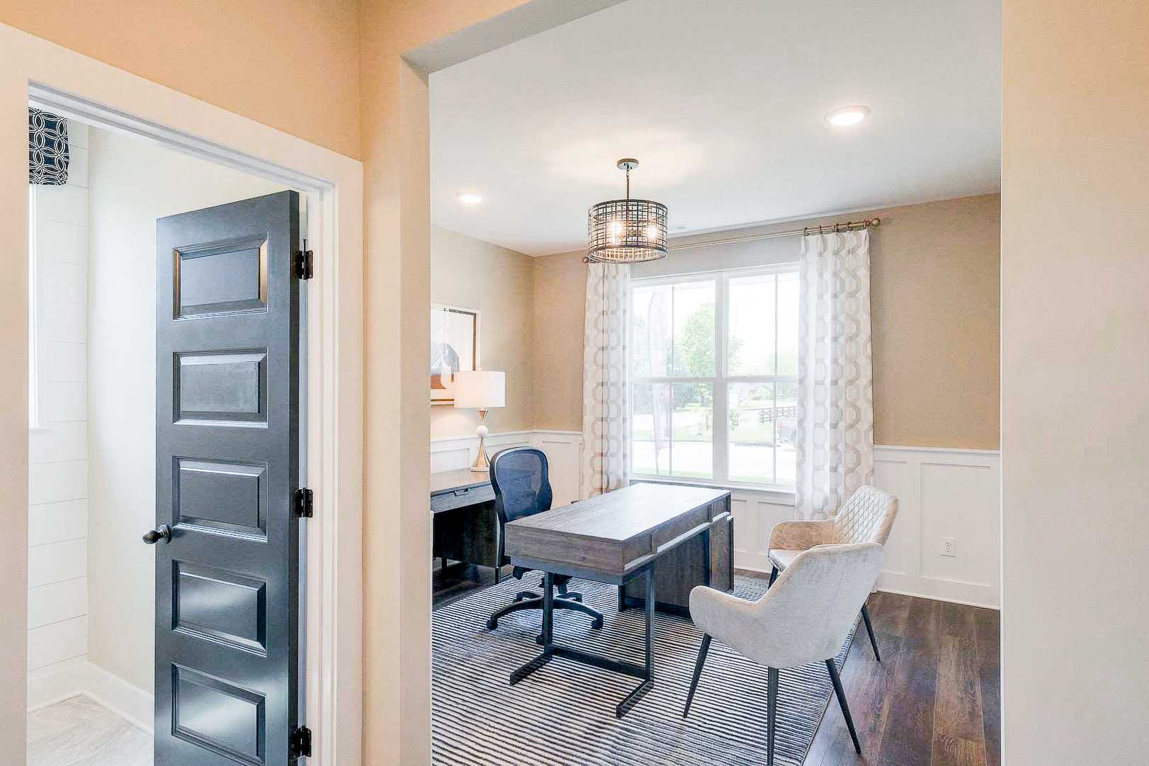 Spacious home office in The Meadows Smyrna TN by Davidson Homes with modern desk, blue door, and neutral tones