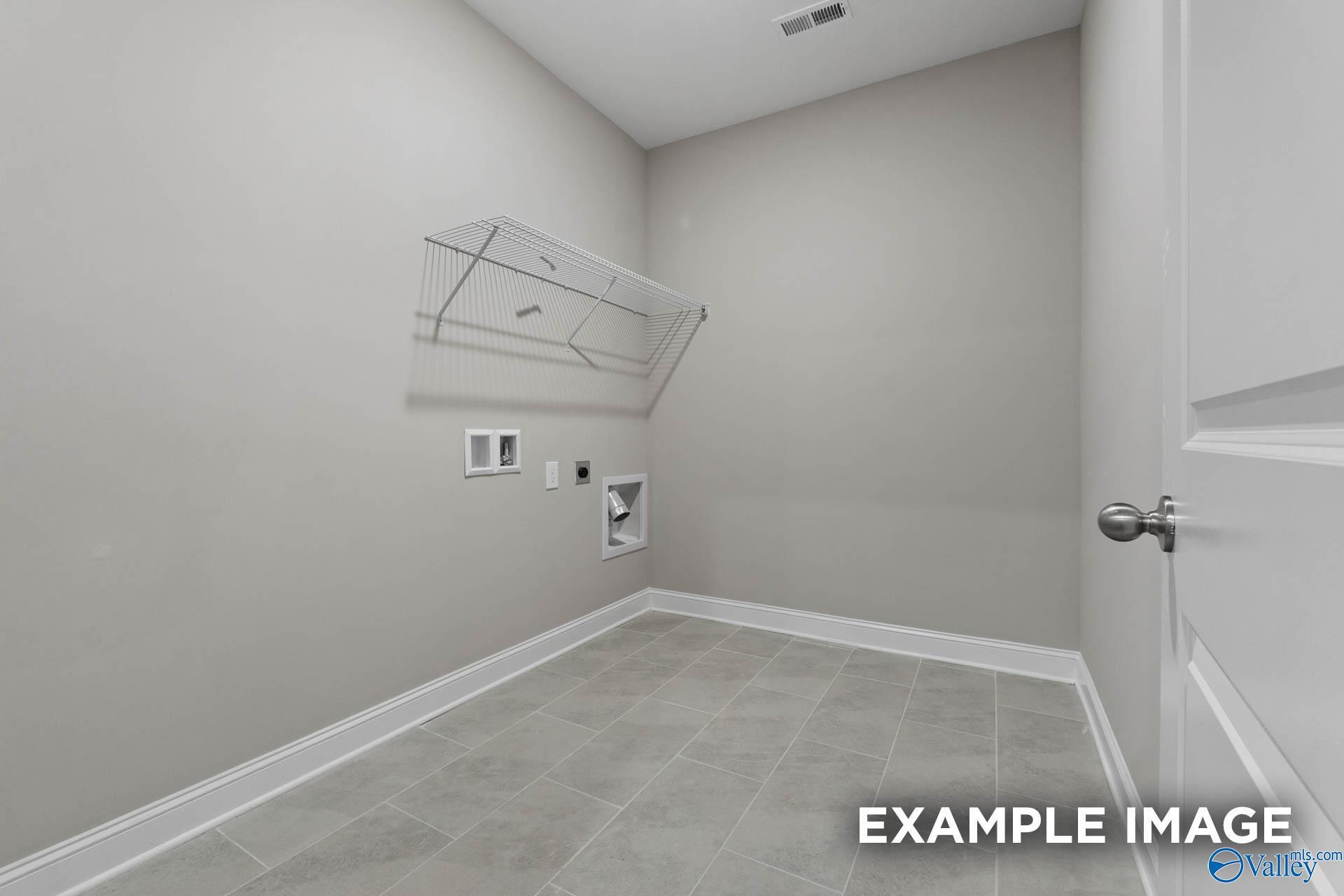 Functional laundry room with wall-mounted drying rack, washer/dryer hookups, and tiled floor in The Finleigh by Davidson Homes, Harvest, AL