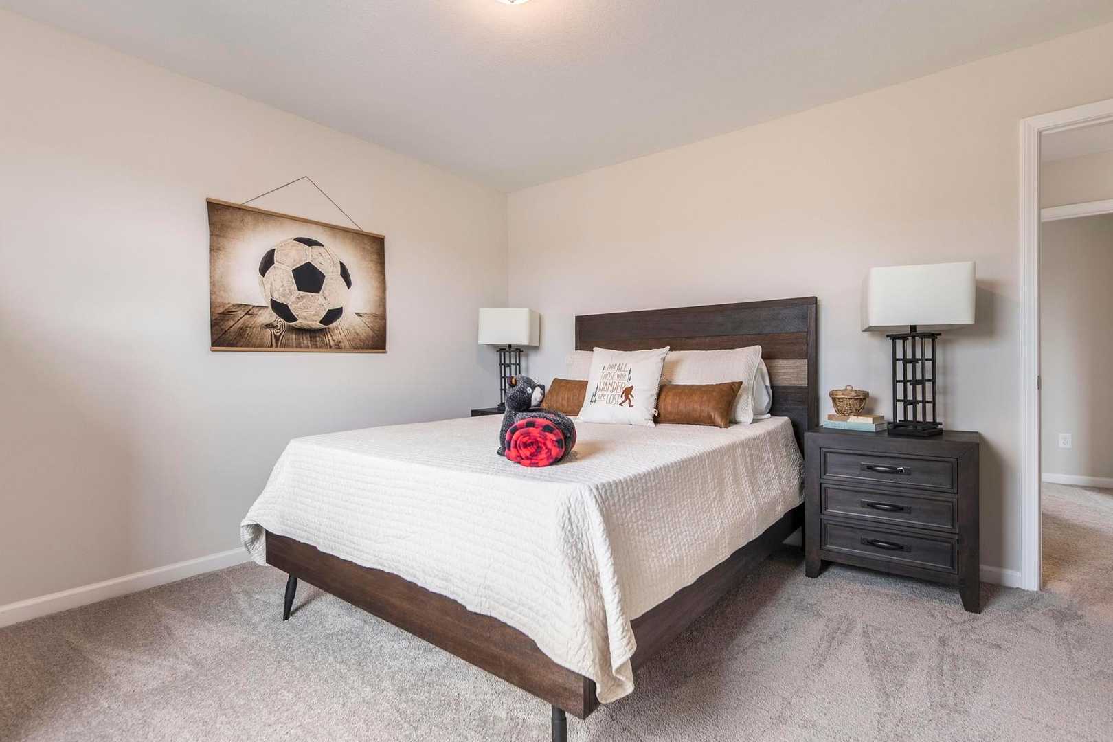 Cozy soccer-themed bedroom at Cape Reserve Donahue Ridge Auburn AL with wooden bed frame, plush pillows, nightstands, and wall art