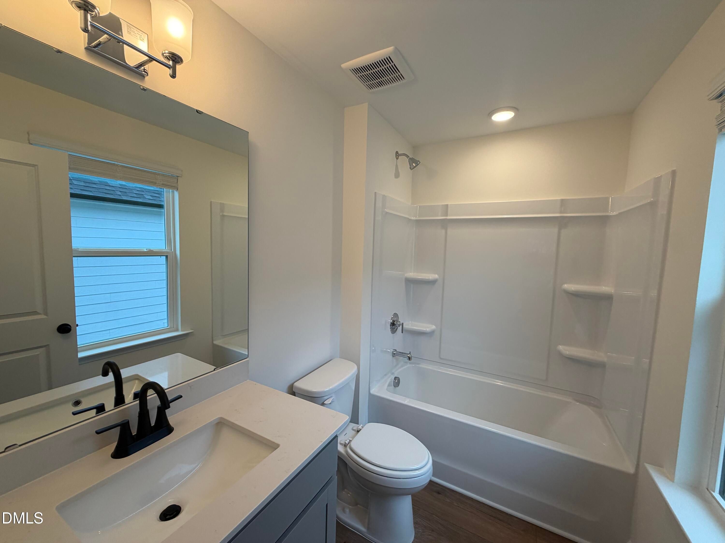Modern bathroom with white vanity, matte black faucet, and tub-shower combo in Davidson Homes' The Ashport M, Wendell Ridge, NC