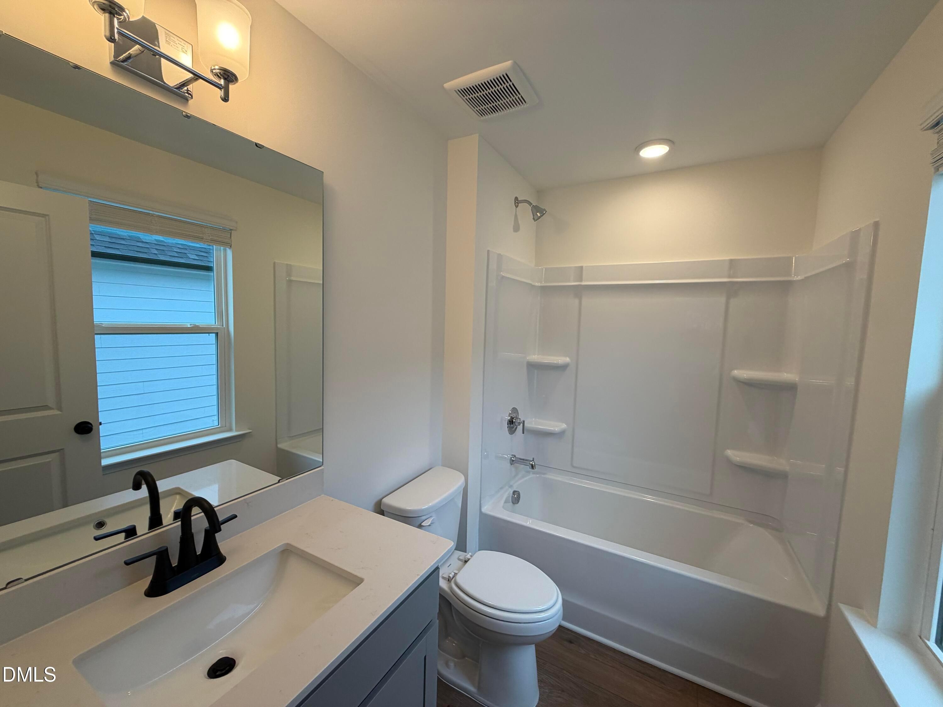 Modern bathroom with white vanity, matte black faucet, and tub-shower combo in Davidson Homes' The Ashport M, Wendell Ridge, NC
