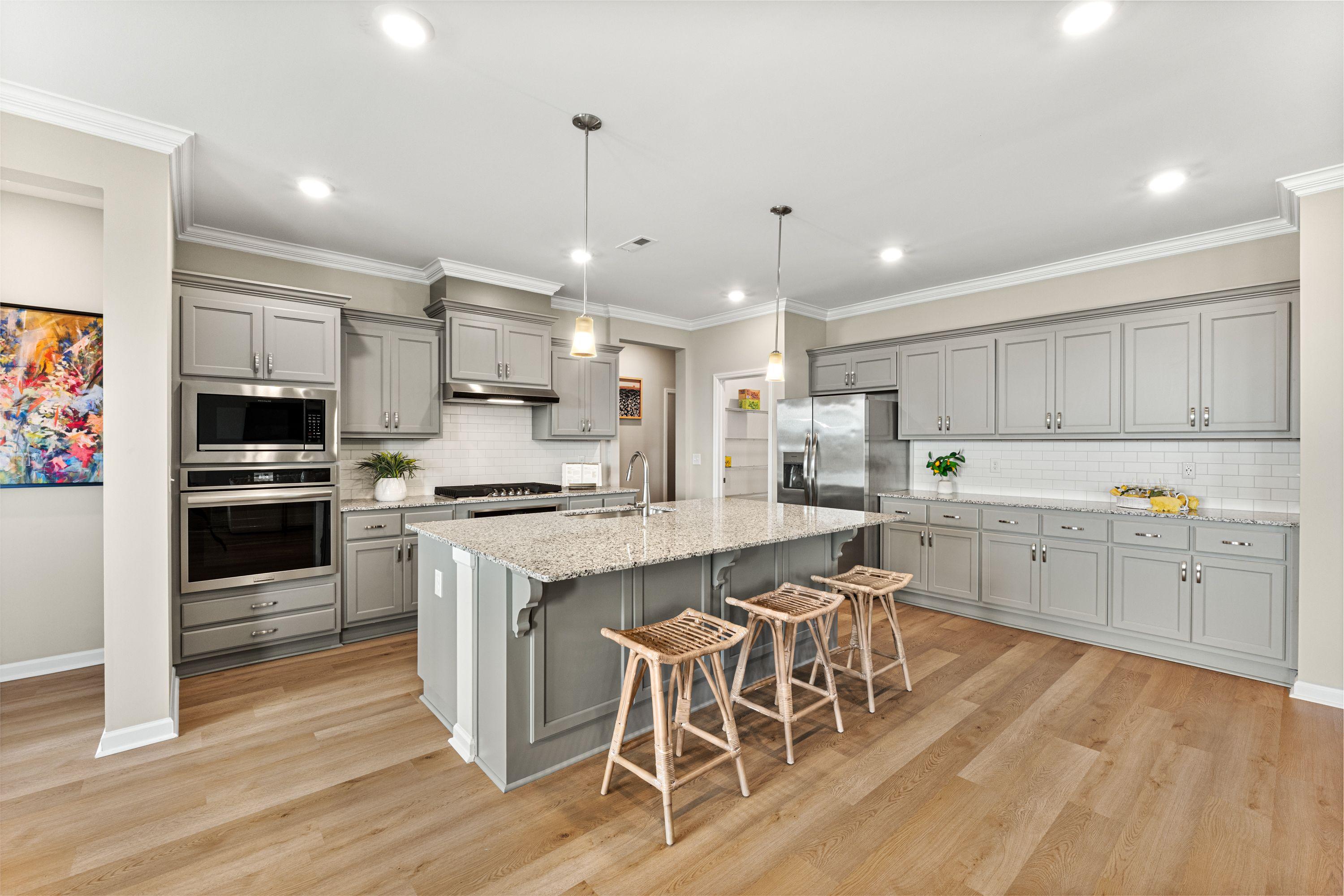Modern gray kitchen with quartz island, stainless appliances, and hardwood floors at Anderson Farm in Athens, Alabama