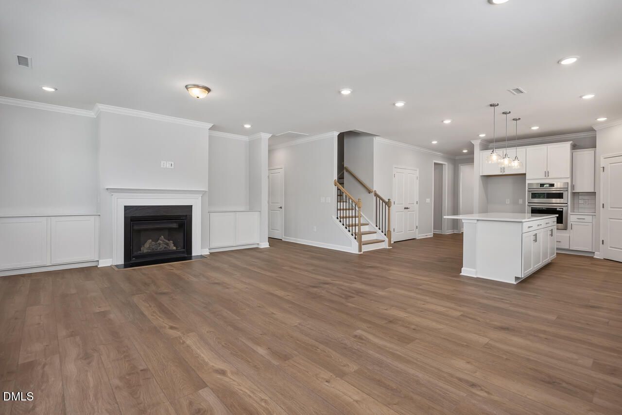 Open-plan living area with fireplace and modern kitchen in The Ashport L at Sage on North Main, Wake Forest, NC.