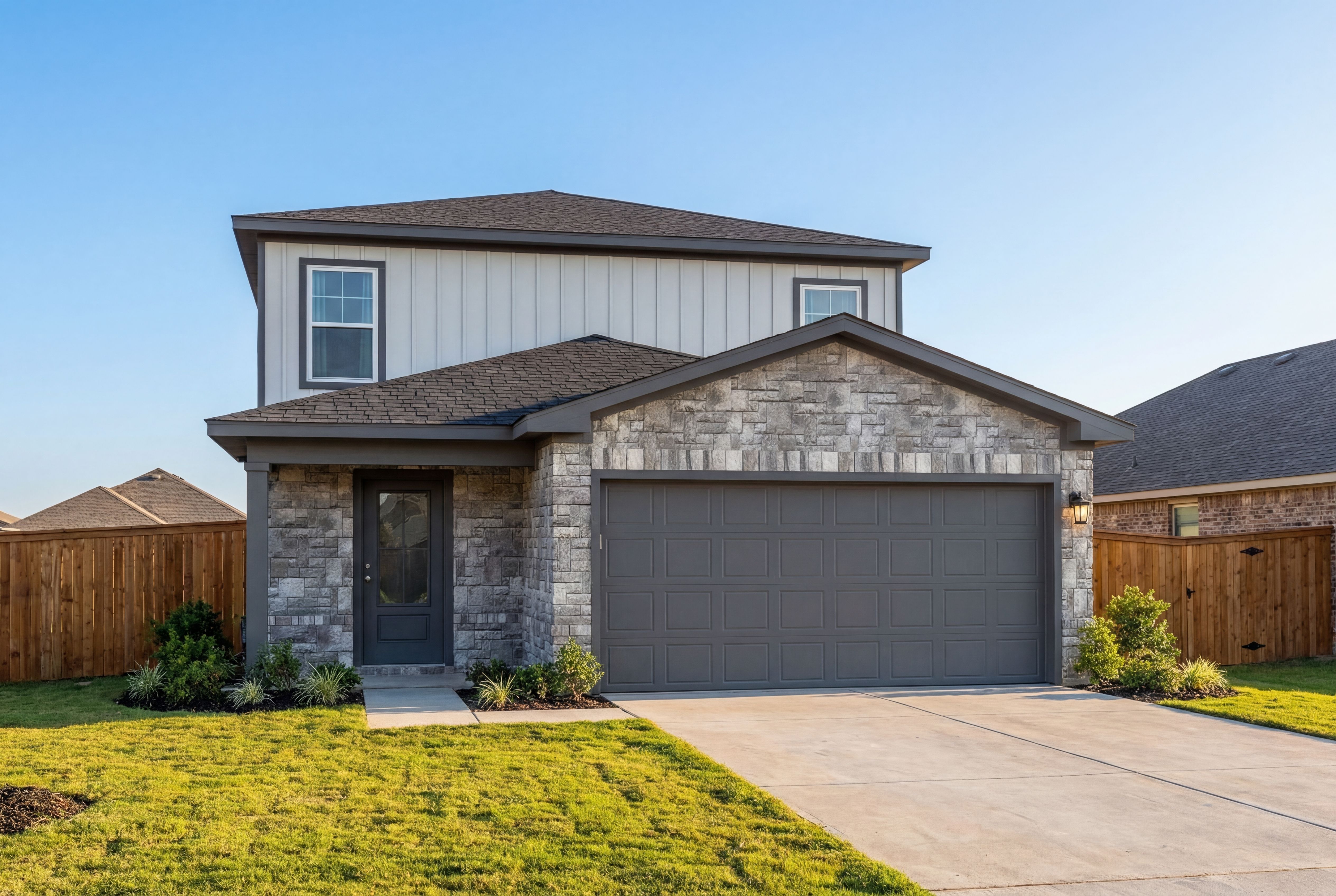 Two-story San Marcos home elevation with stone and gray siding, double garage, and landscaped yard in Heartland, Texas