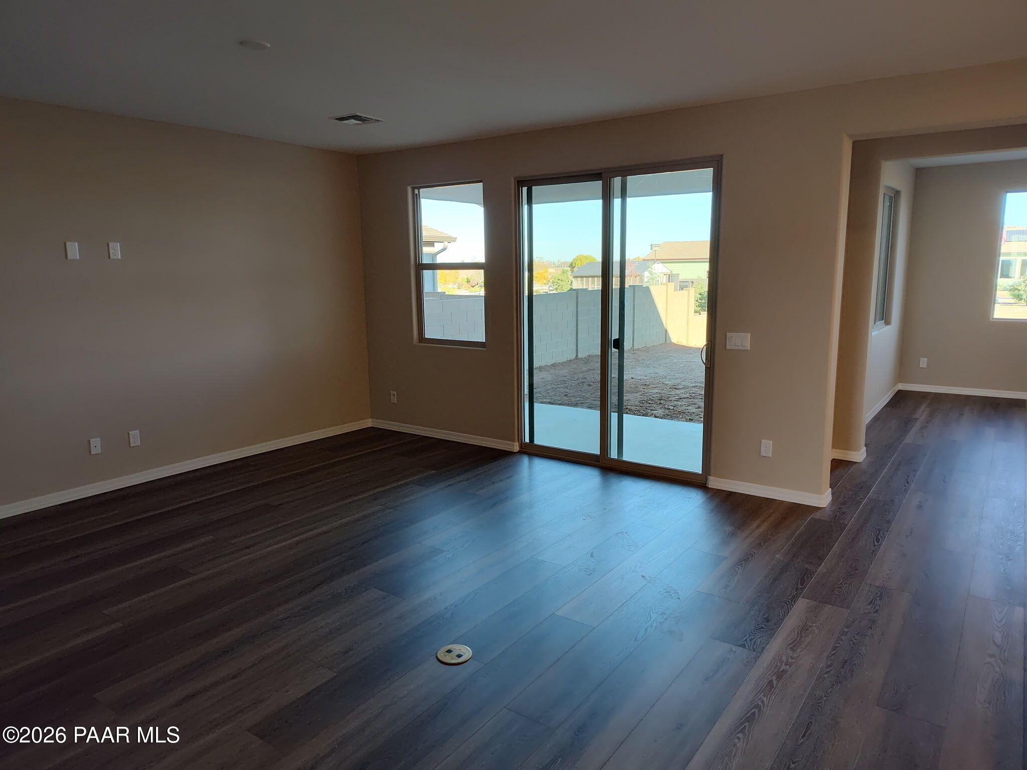Spacious living area with luxury vinyl plank flooring and sliding glass door to backyard in Inspiration C, Pronghorn Ranch.