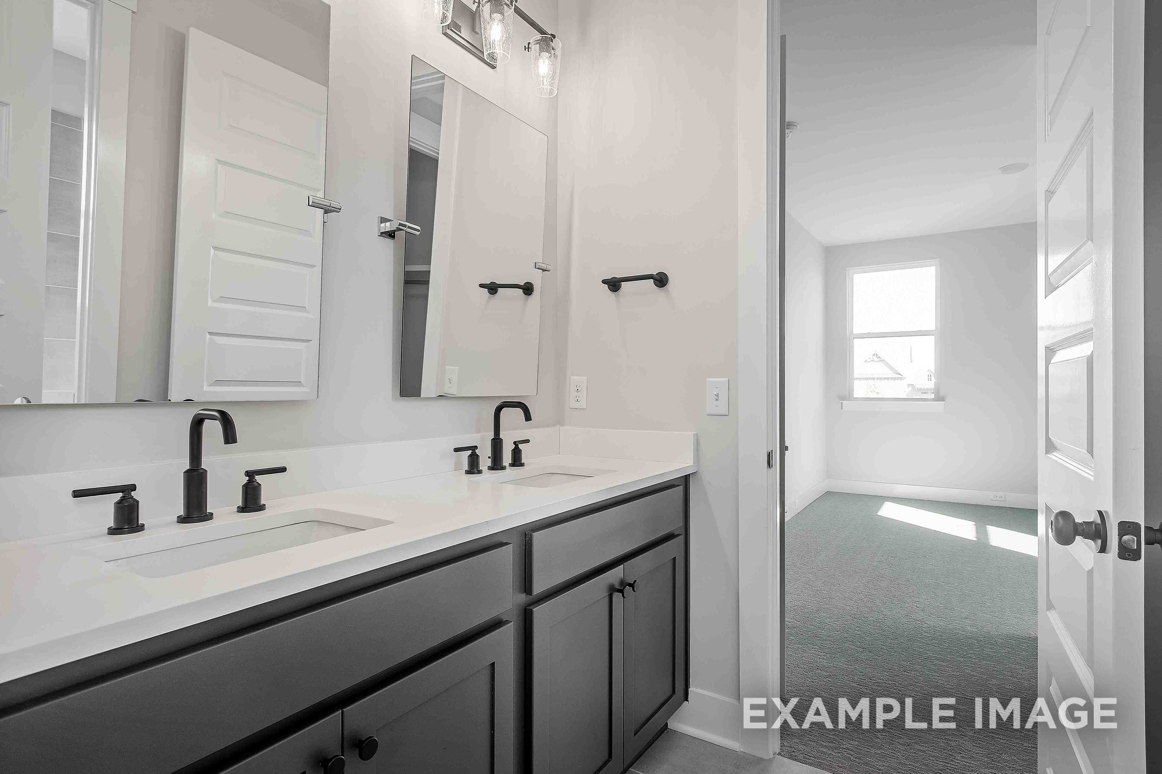 Spacious master bathroom in The Alston A featuring double vanity, large mirrors, and open door to bedroom
