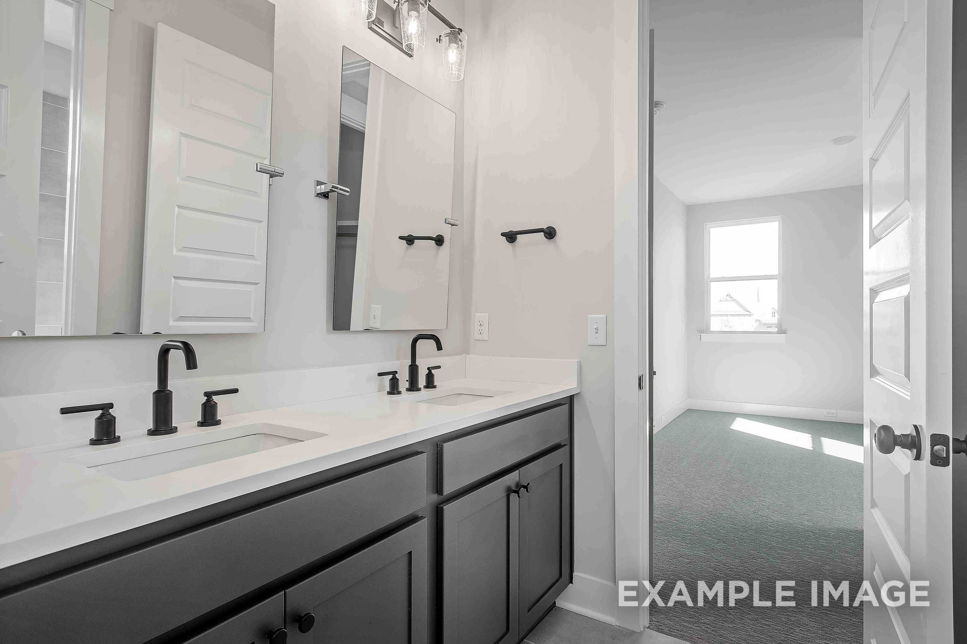 Spacious master bathroom in The Alston A featuring double vanity, large mirrors, and open door to bedroom