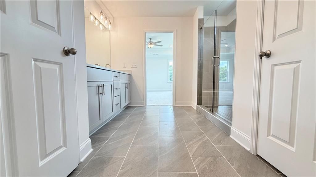 Modern master bathroom with gray vanity, glass-enclosed shower, and tile flooring in Davidson Homes Hickory C floor plan.