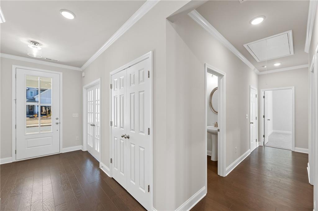 Bright hallway with white doors, powder room mirror and sink, hardwood floors in Davidson Homes The Harrison G, Hoschton, GA