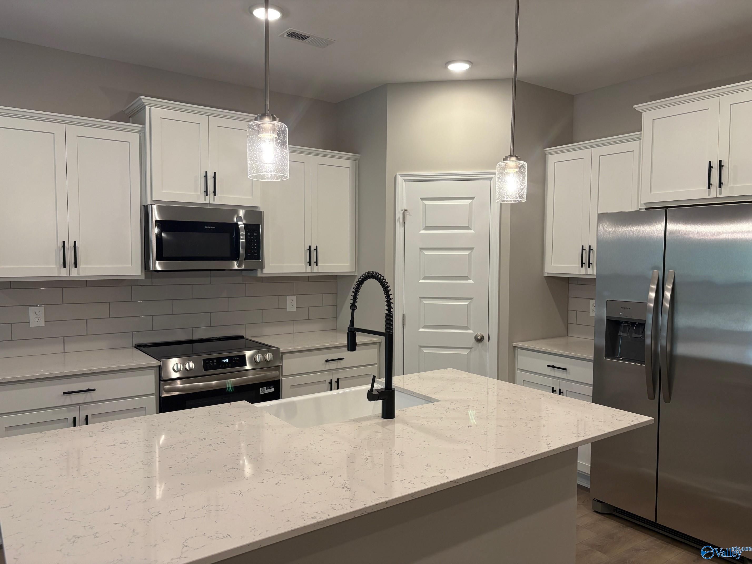 Modern white kitchen with quartz island, stainless appliances, subway tile backsplash in The Asheville C, Arab, Alabama
