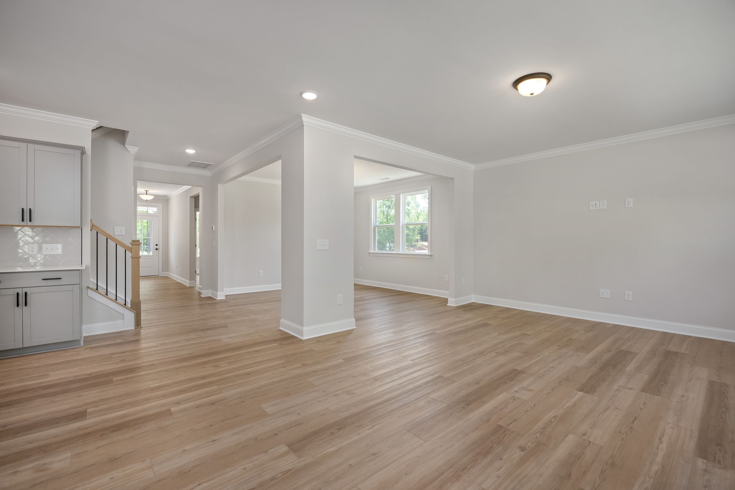 Spacious open-concept foyer in The Beech A home design with light oak hardwood floors, white cabinetry, and arched entryways