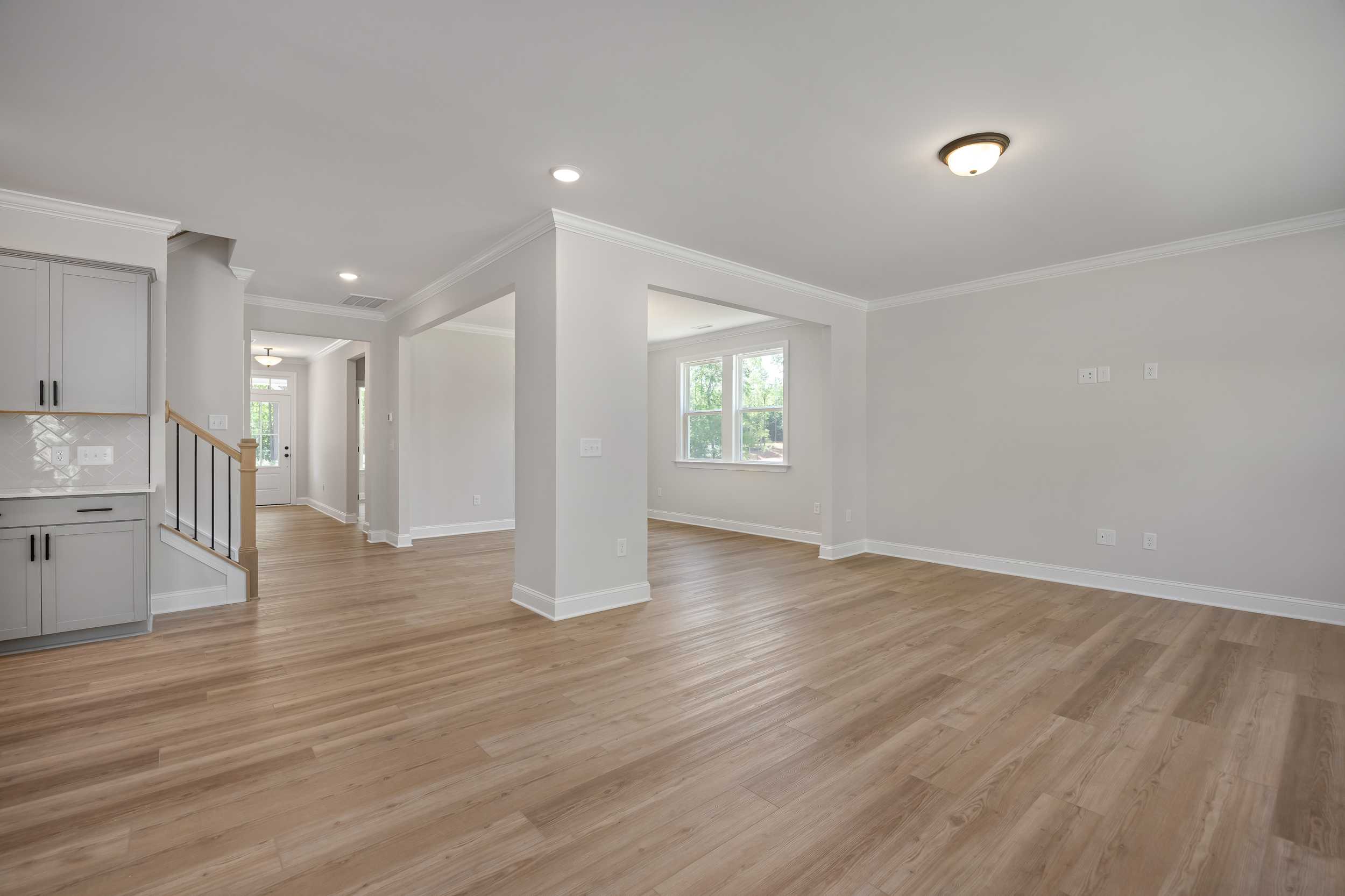 Spacious open foyer in The Beech C home design featuring light hardwood floors, arched openings, and modern white cabinets