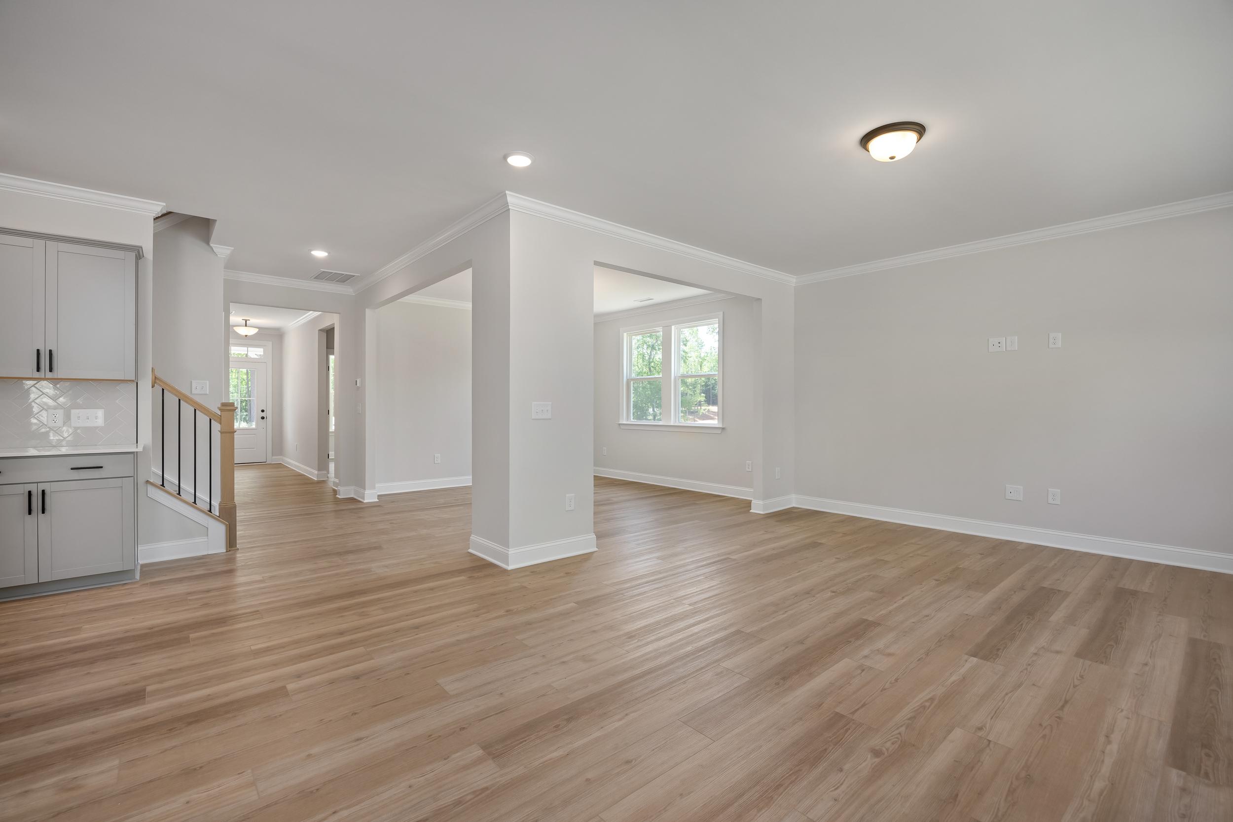 Spacious open-concept foyer in The Beech A home design with light oak hardwood floors, white cabinetry, and arched entryways