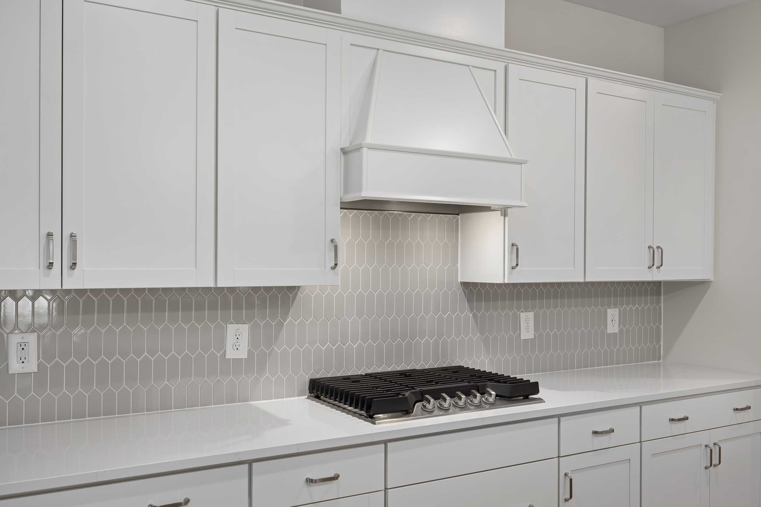 Modern Beech A kitchen featuring white shaker cabinets, hexagonal gray subway tile backsplash, and gas range