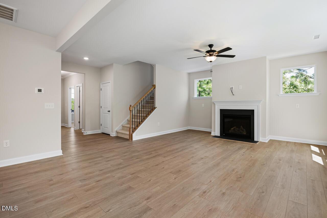 Spacious living room with fireplace, wood-look flooring, and staircase in The Chestnut floor plan, Montrose, Aberdeen, NC.