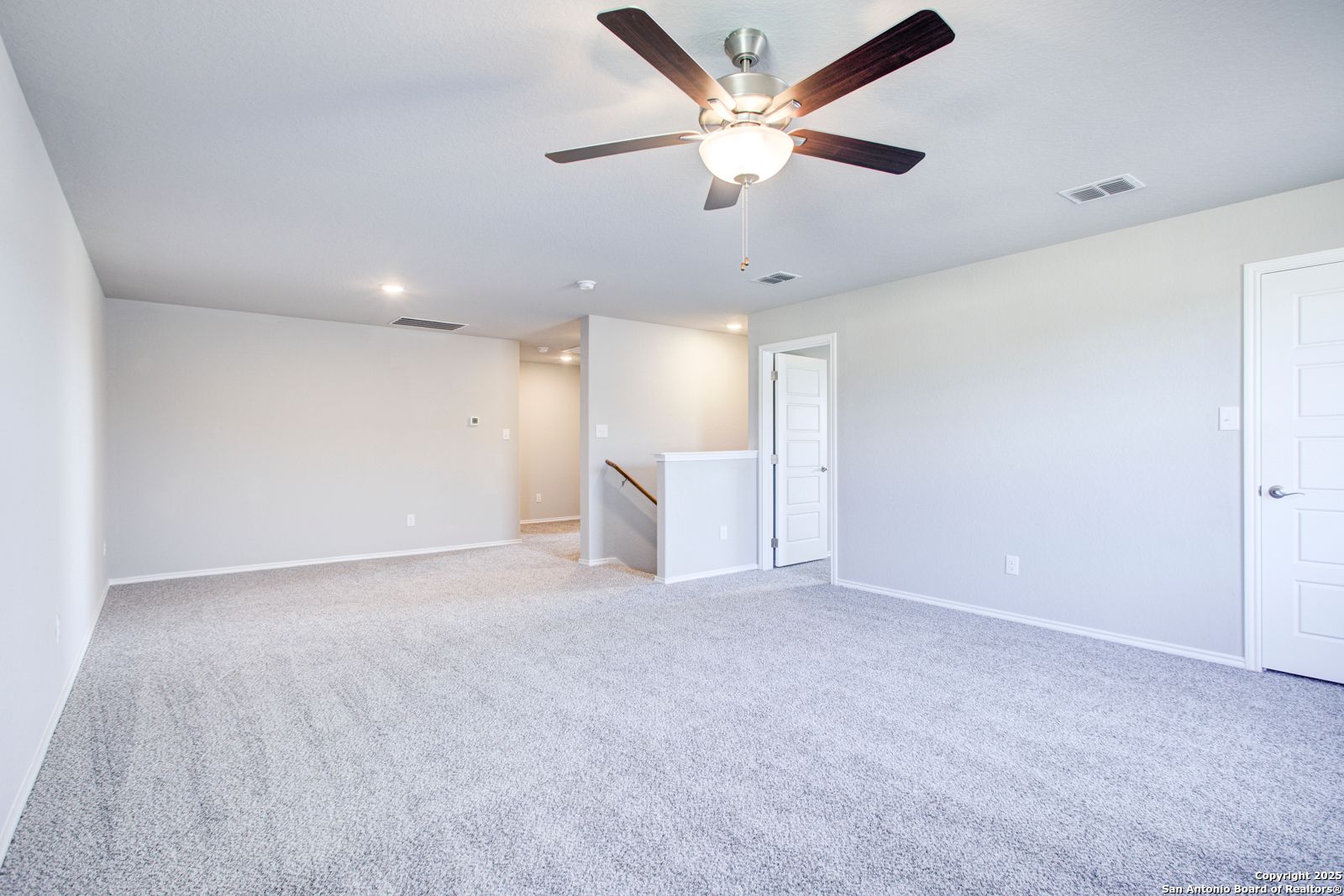 Spacious two-story foyer with gray carpet, ceiling fan, staircase, and doors in Davidson Homes The Douglas G, San Antonio