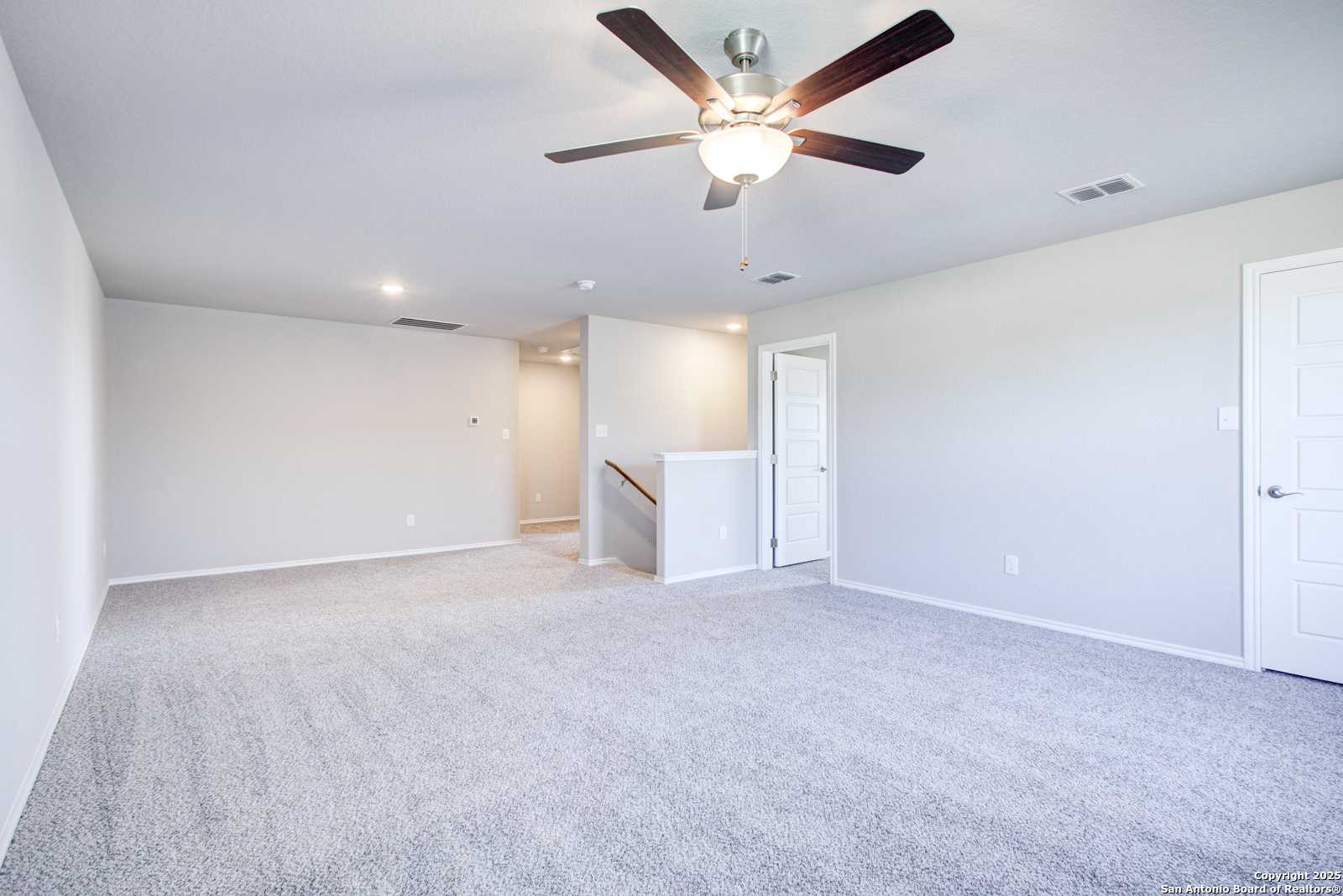 Spacious two-story foyer with gray carpet, ceiling fan, staircase, and doors in Davidson Homes The Douglas G, San Antonio