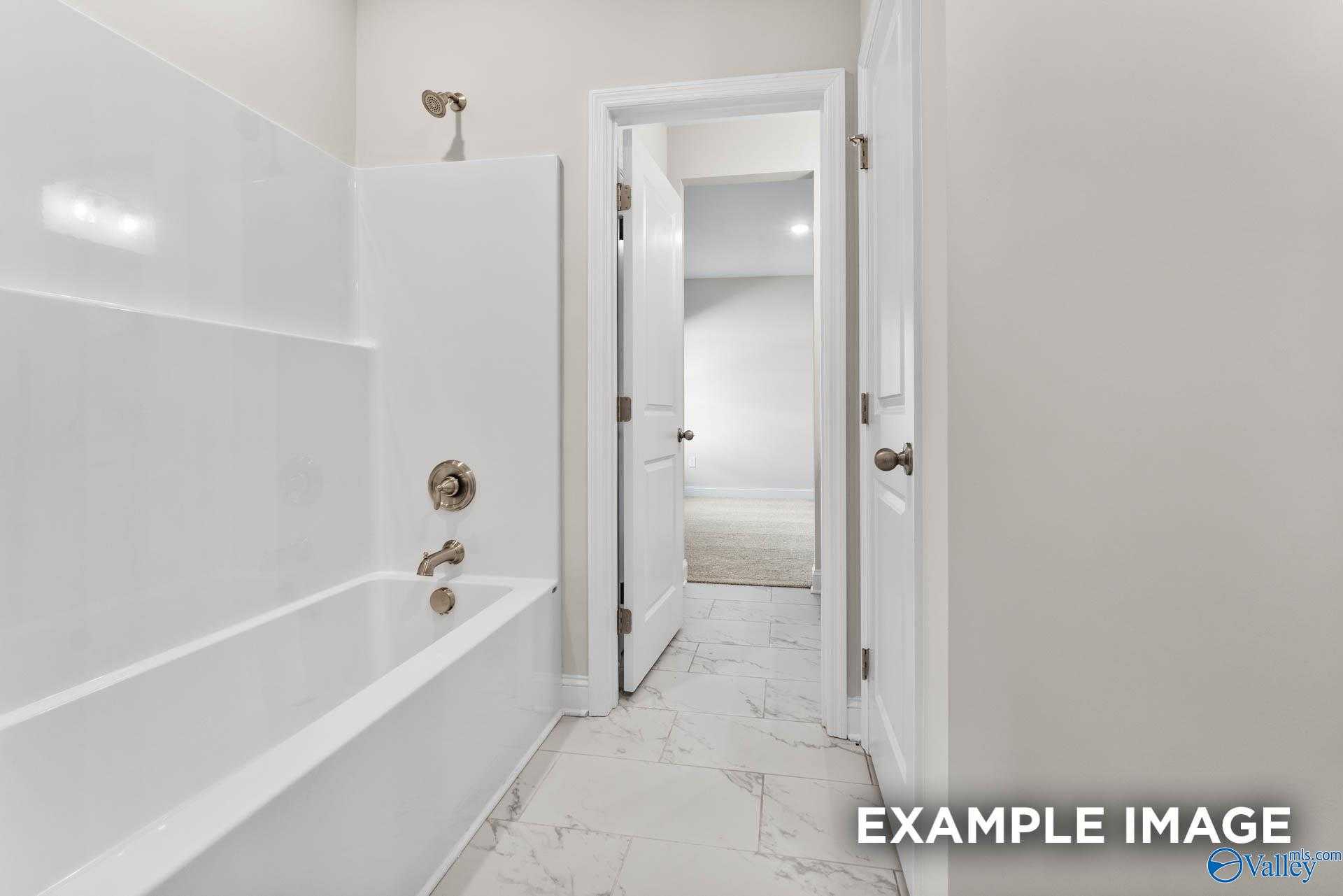 Elegant master bathroom with white tub, glass shower, and marble-look tile floor in Davidson Homes The Finleigh, Meridianville, Alabama