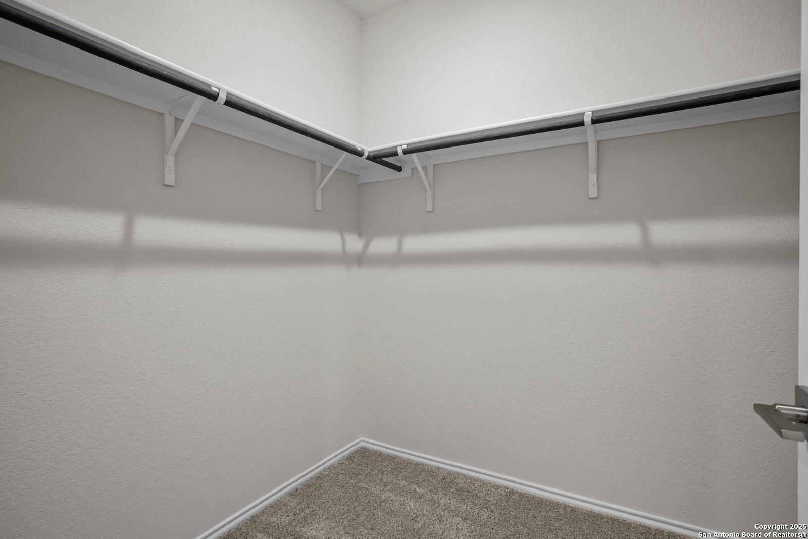 Spacious walk-in closet with built-in shelves and hanging rods in Davidson Homes The Asheville J, Comanche Ridge, San Antonio, Texas