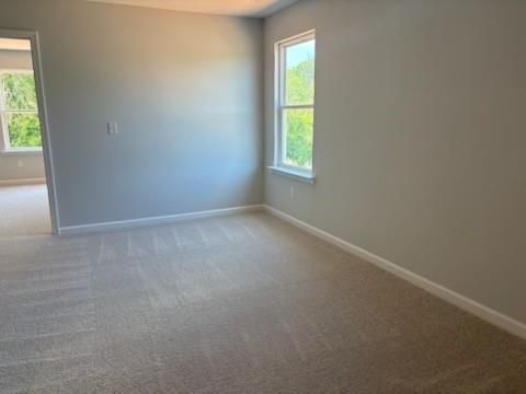 Bright secondary bedroom with neutral gray walls, beige carpet, and large window in Davidson Homes The Rabun A, Winder, GA