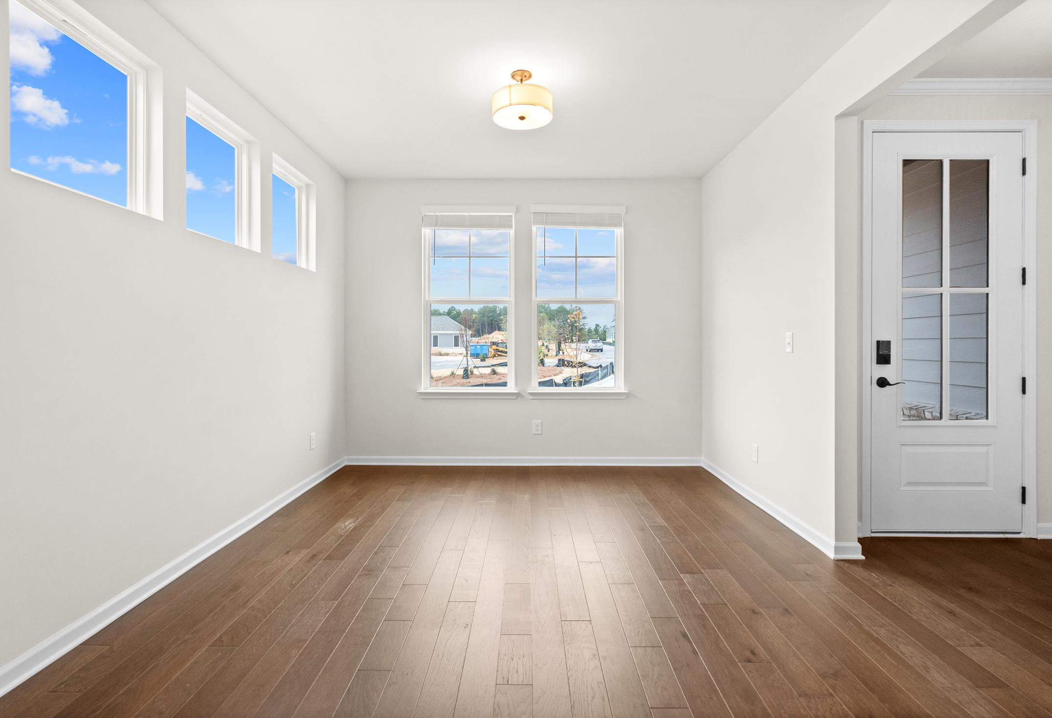 Bright living room in The Glenwood home design with large windows, hardwood floors, and natural light in Loganville GA
