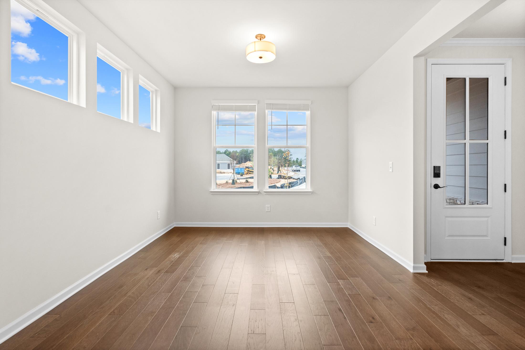 Bright living room in The Glenwood home design with large windows, hardwood floors, and natural light in Loganville GA