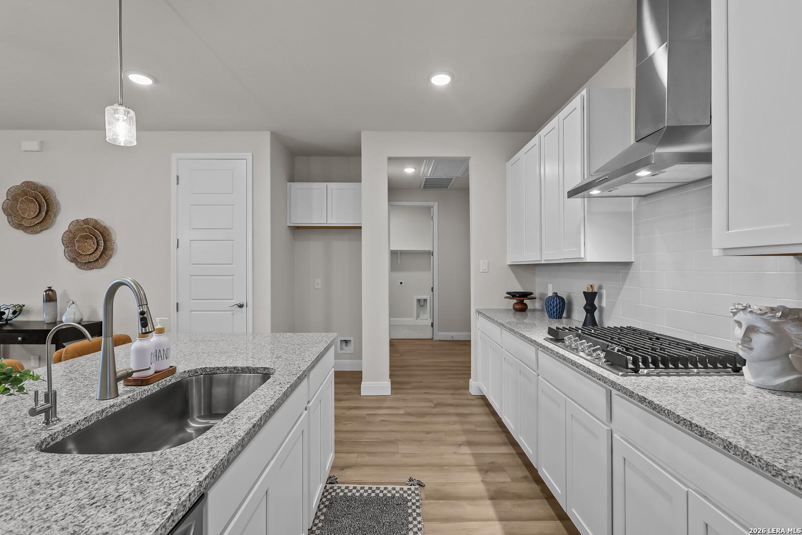 Modern kitchen with granite countertops, white cabinets, and stainless appliances in The Lanier H plan, Ladera San Antonio.