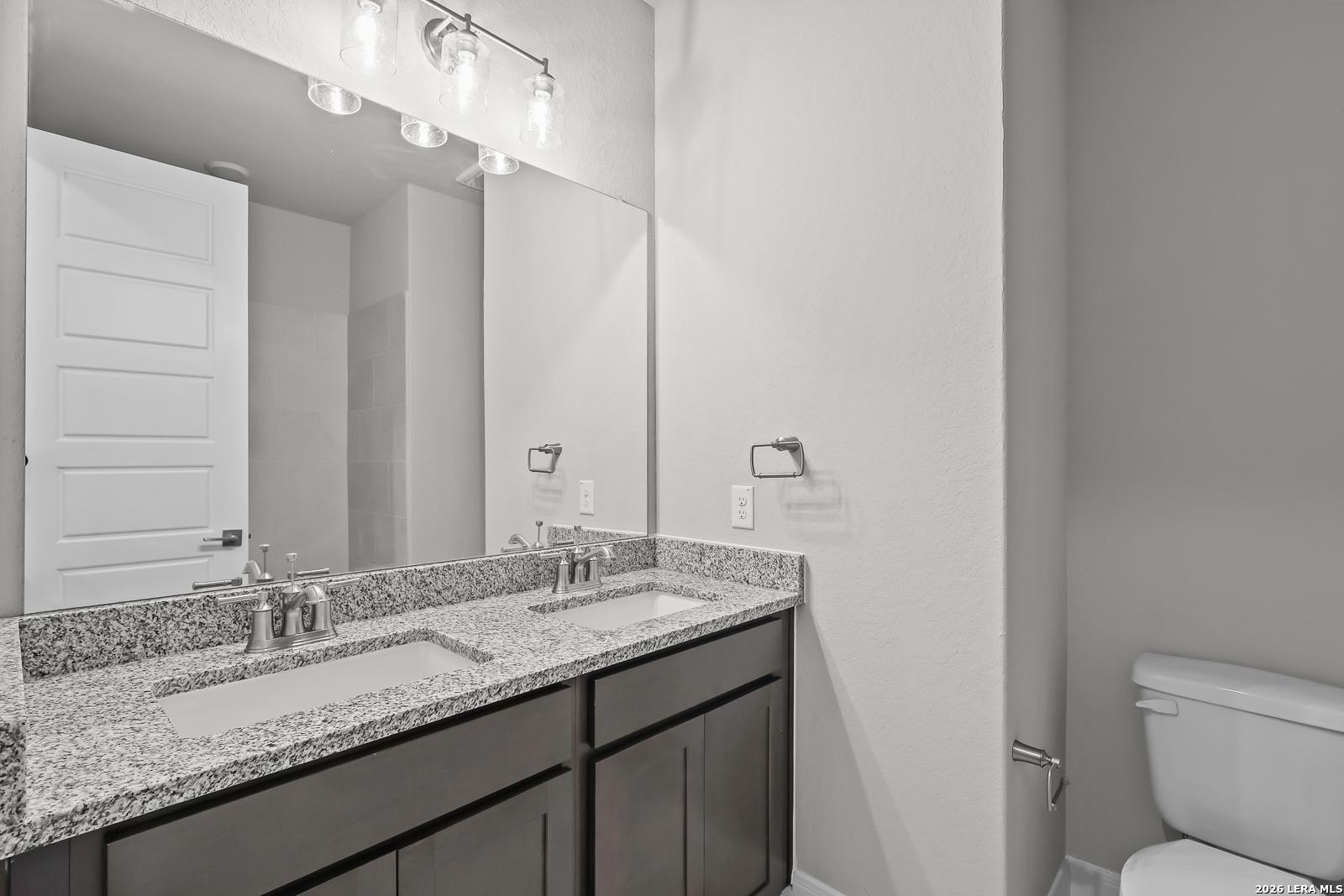 Modern master bathroom featuring double granite vanity, mirrors, and toilet in Davidson Homes The Rockford G, Ladera, San Antonio