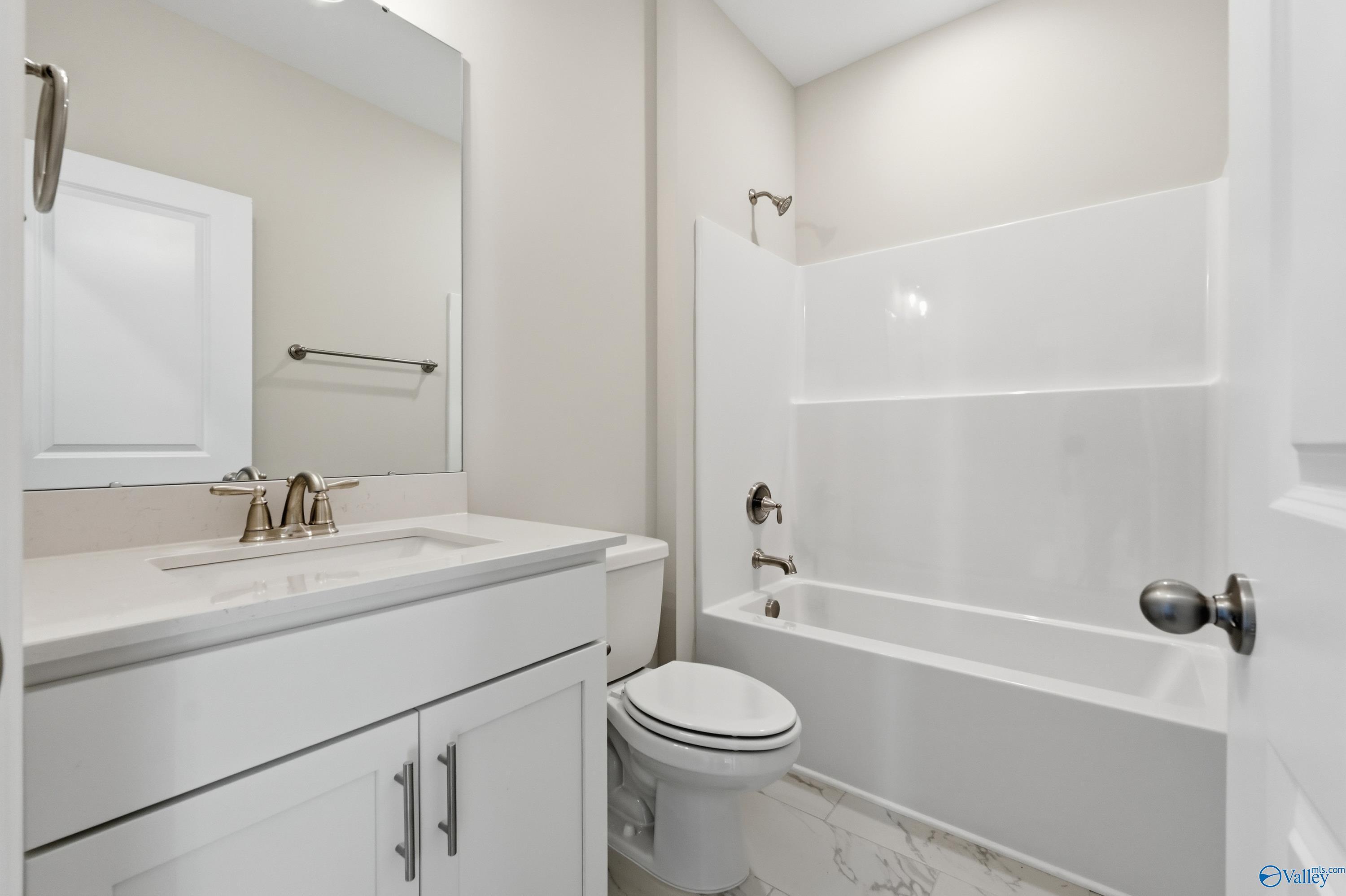 Bright bathroom with white vanity, soaking tub, shower combo, and toilet in Davidson Homes The Montgomery B, Toney, Alabama