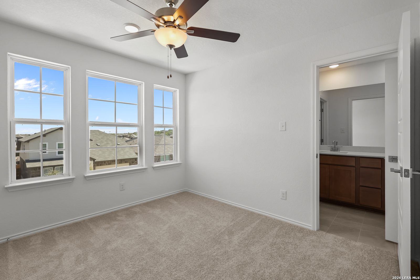 Bright secondary bedroom with dual ceiling fans, large windows, and attached bath in Davidson Homes The Sequoia B, San Antonio