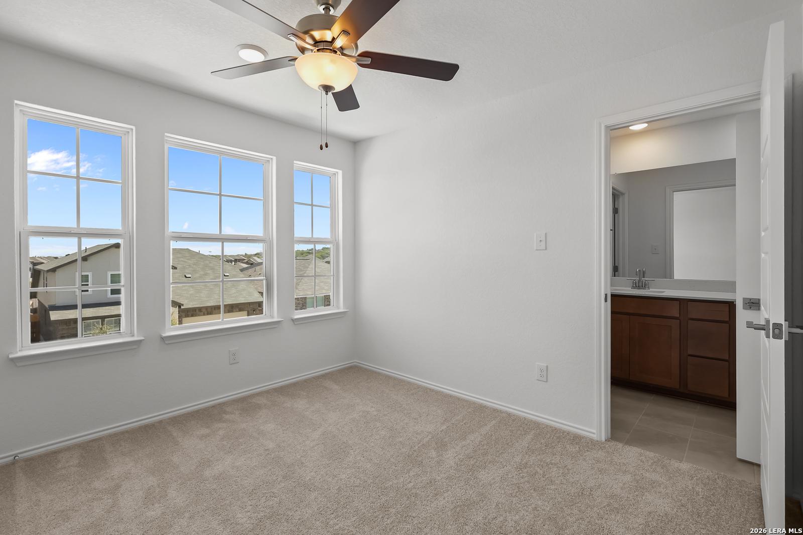 Bright secondary bedroom with dual ceiling fans, large windows, and attached bath in Davidson Homes The Sequoia B, San Antonio