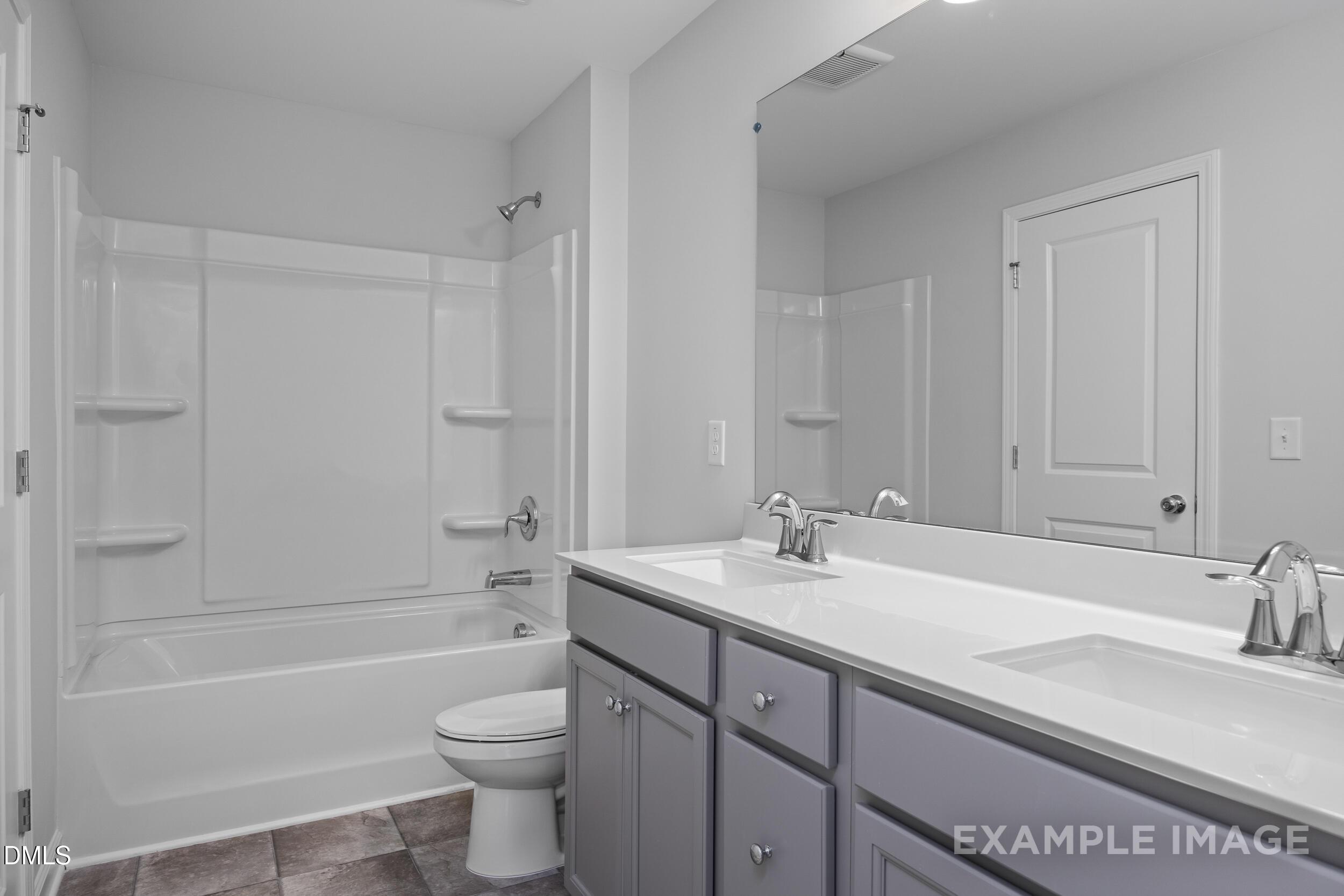 Modern bathroom with dual vanity, white tub-shower combo, and gray cabinetry in The Gavin A home, Gregory Village, Lillington.