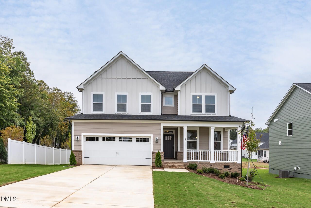 Modern two-story gray-sided home with 2-car garage, covered porch, and flag in Sage on North Main, Wake Forest, NC