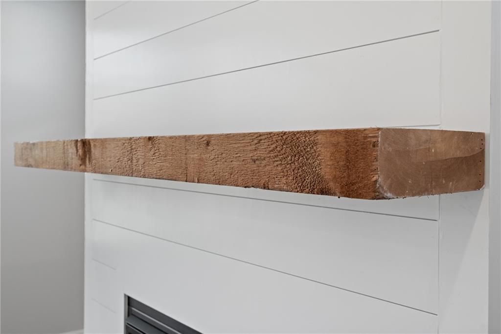 Rustic wooden beam mantel over black fireplace insert on white shiplap wall in Davidson Homes The Hickory A, Winder, Georgia